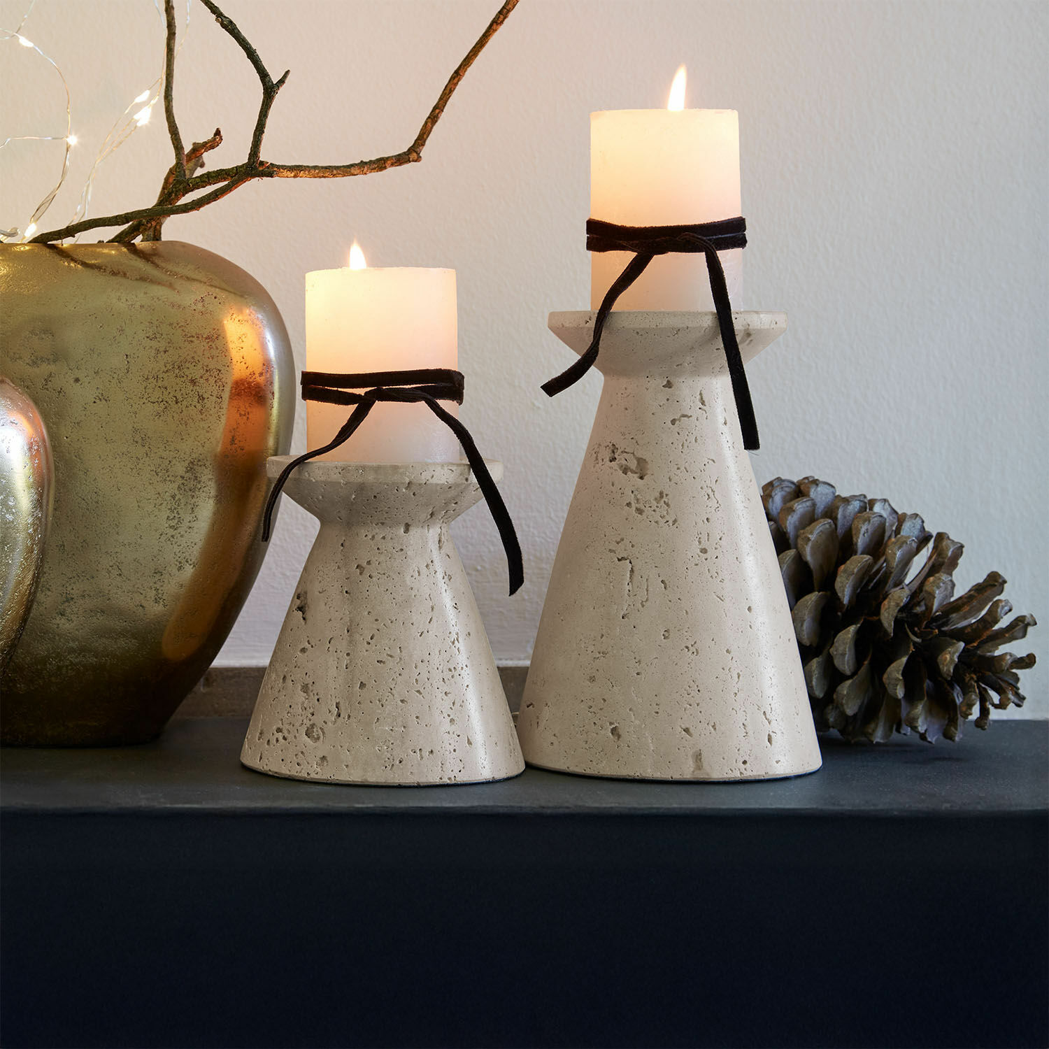 Kaarsenhouder set van 2 Bazrahim Twee beige betonnen kandelaren met witte kaarsen en zwarte linten op een decoratieve tafel