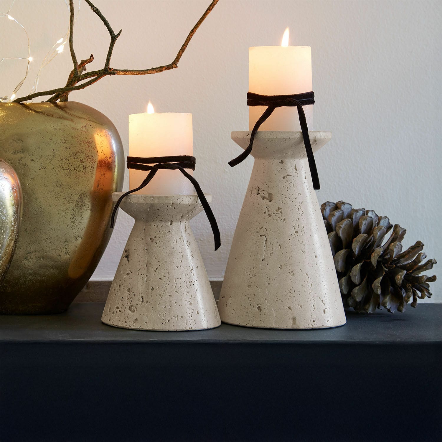 Kaarsenhouder set van 2 Bazrahim Twee beige betonnen kandelaren met witte kaarsen en zwarte linten op een decoratieve tafel
