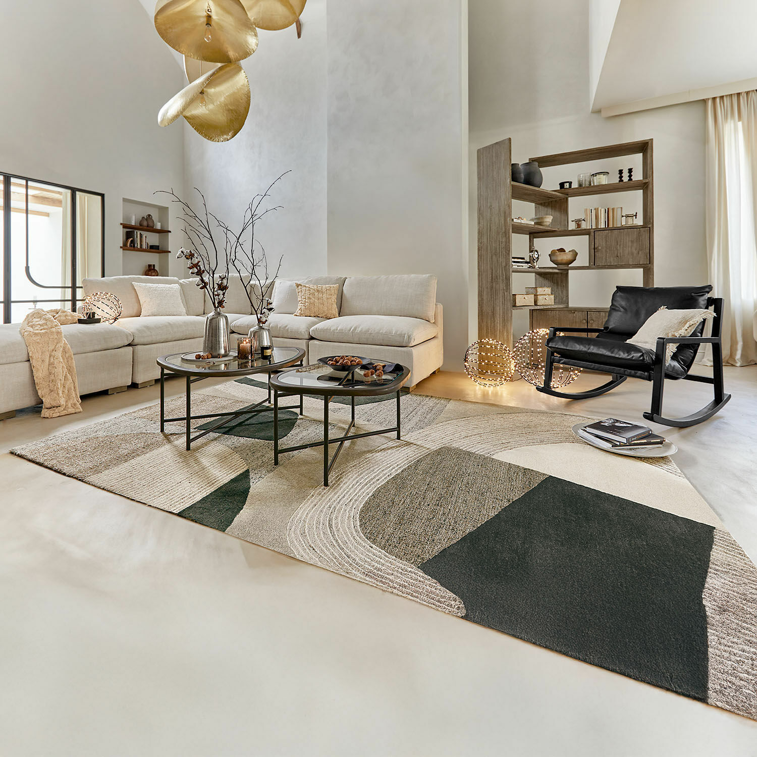 Moderne woonkamer met beige bank, zwarte schommelstoel en geometrisch vloerkleed in neutrale kleuren