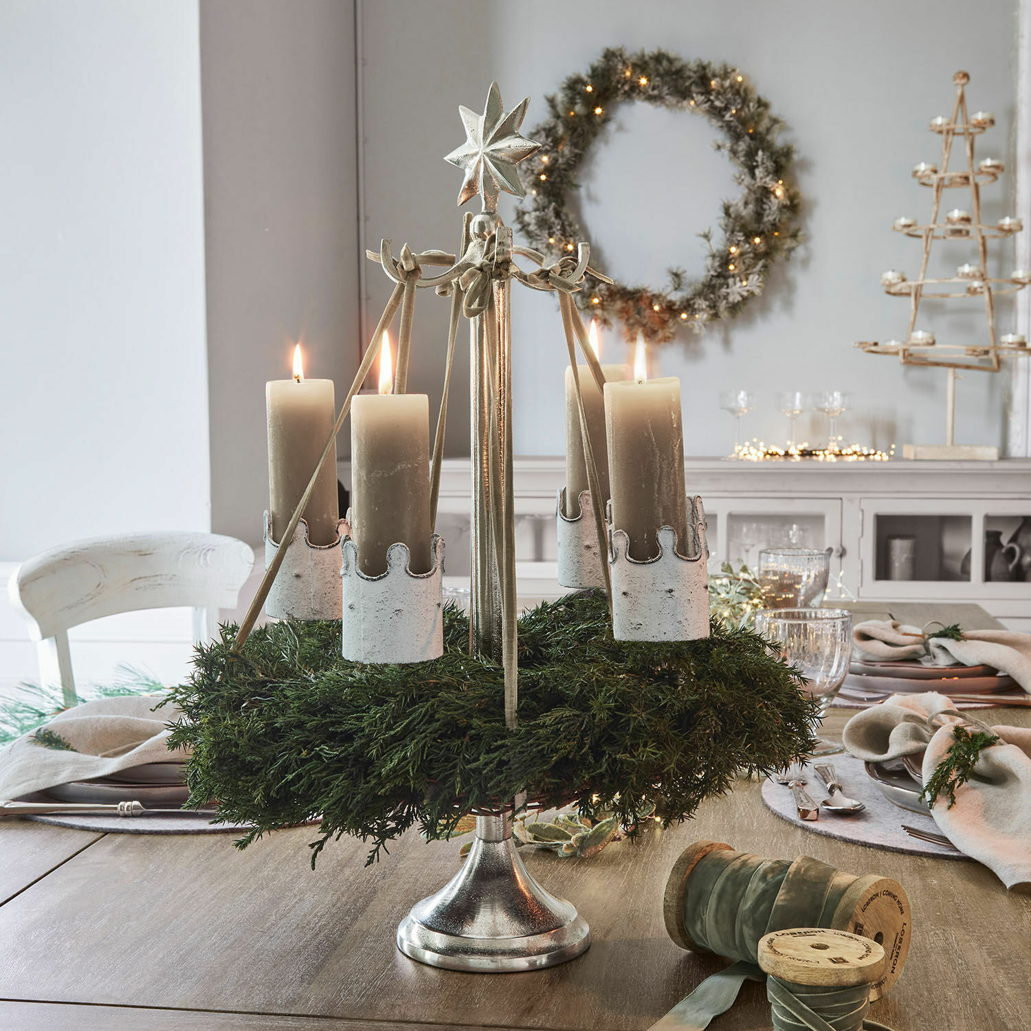 Kranshouder Graham Metalen adventskrans met groene krans en vier beige kaarsen op houten tafel