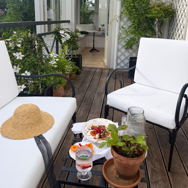 Terras met witte metalen stoelen, houten vloer en potplanten voor een gezellige buitenruimte
