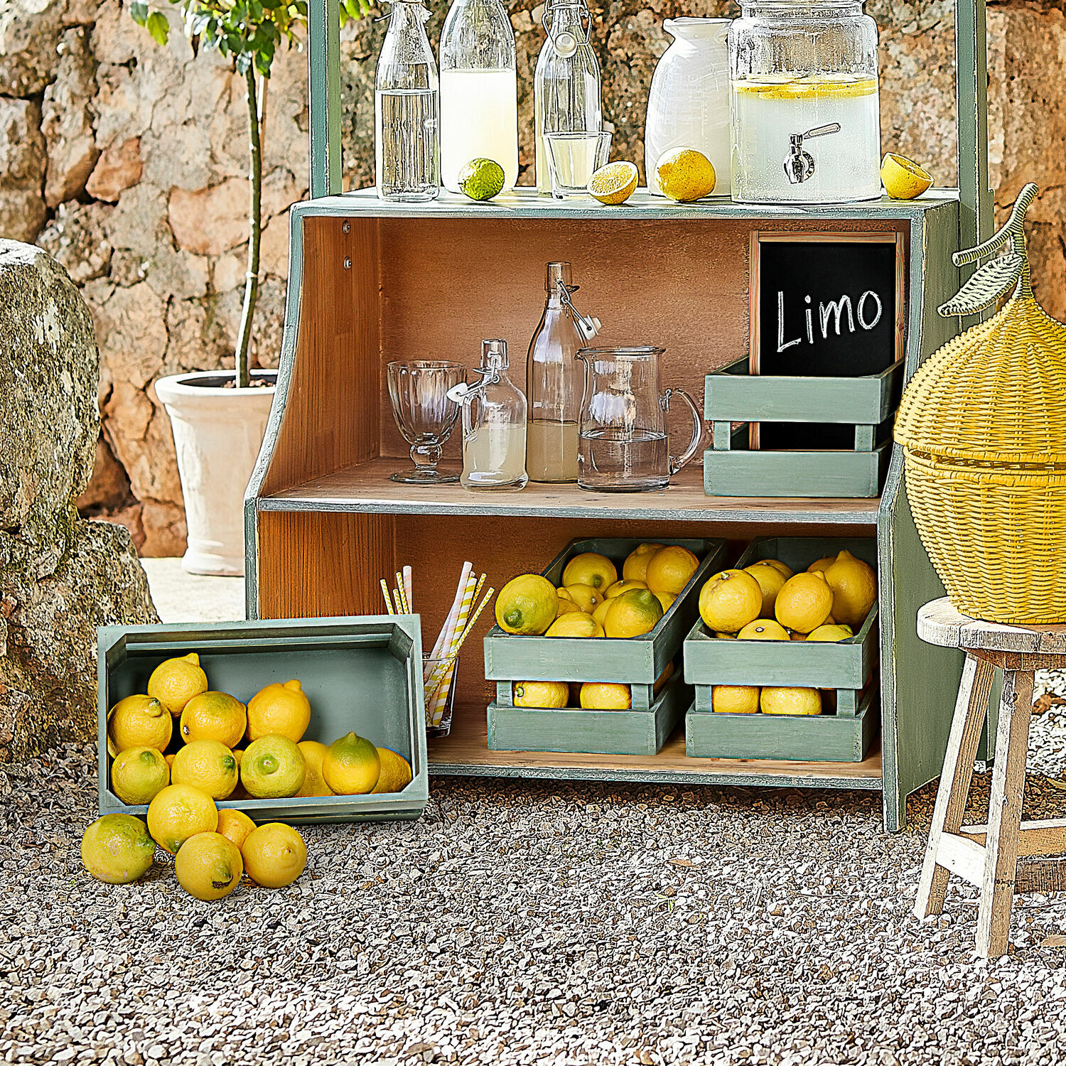Groene houten plank met citroenen en glazen flessen voor limonade buiten