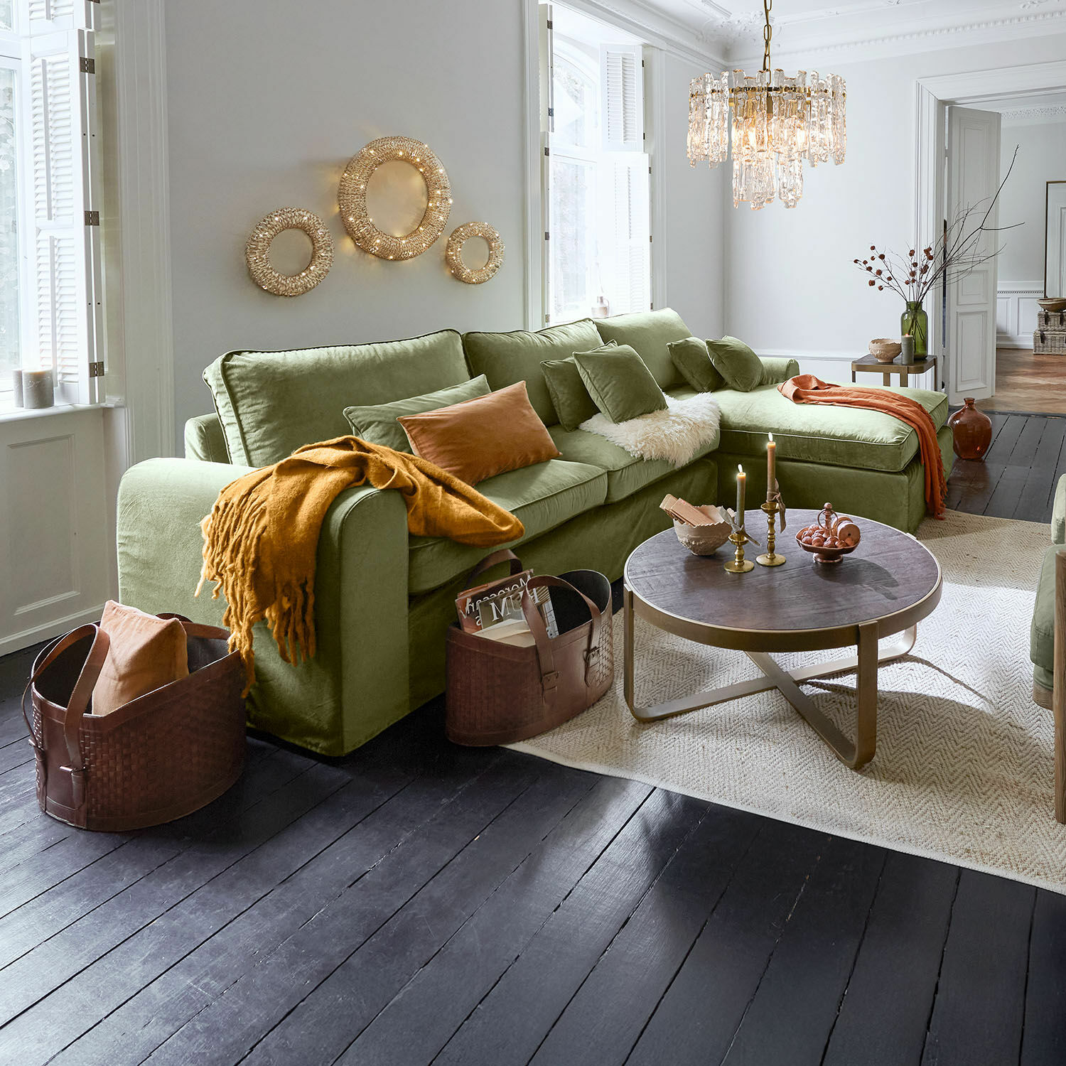 Comfortabele groene hoekbank van zachte stof in woonkamer met donkere houten vloer en decoratieve verlichting