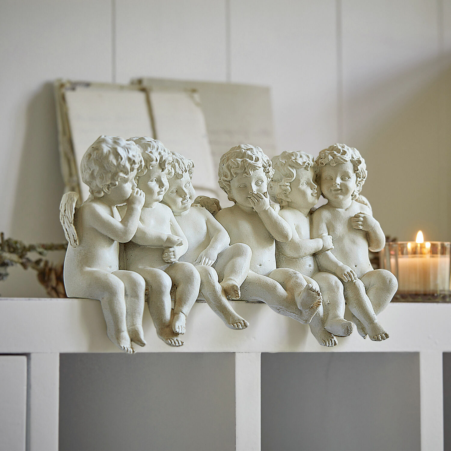 Zes witte engelenfiguren van kunststof op een witte plank, interieurdecoratie