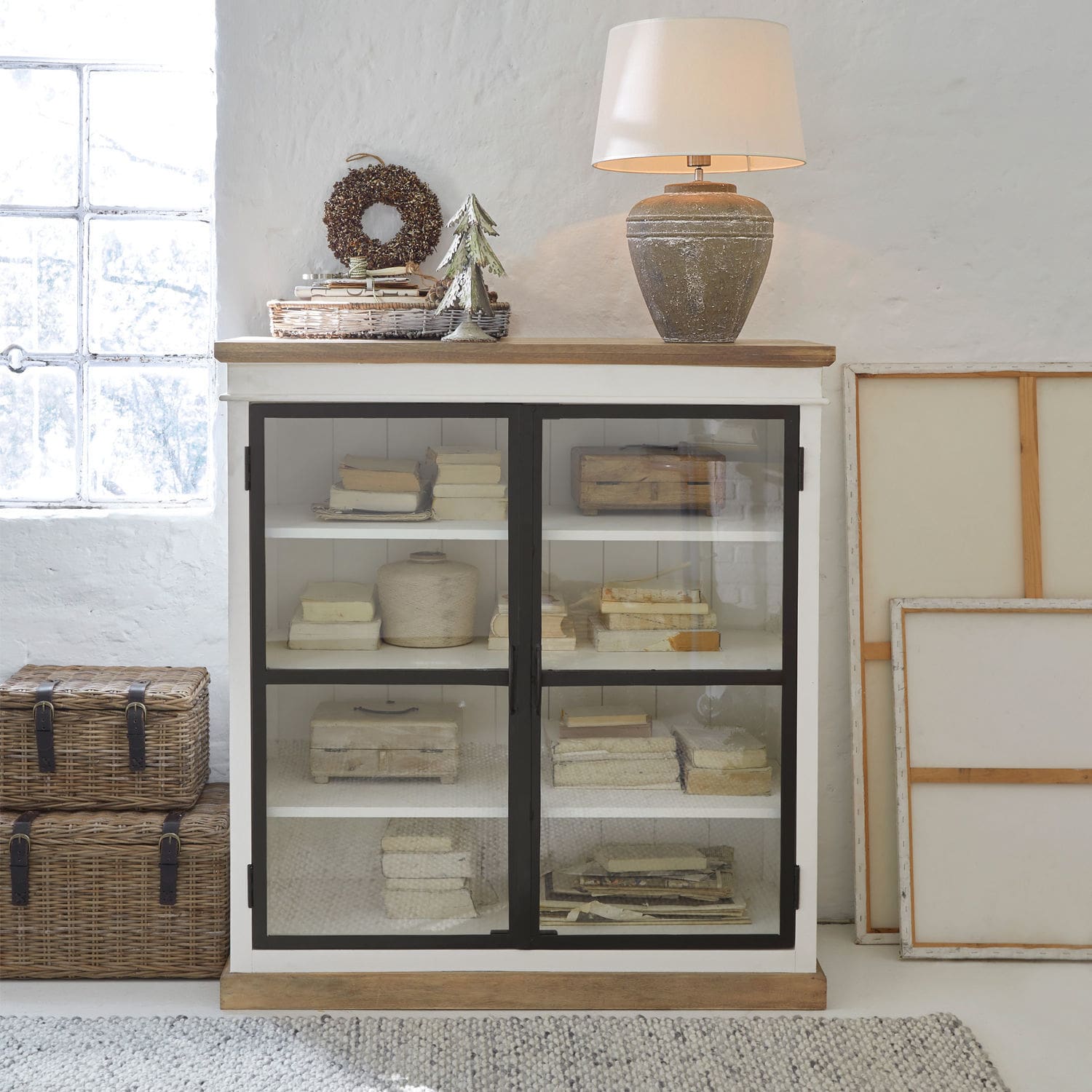 Witte houten kast met glazen deuren en keramische lamp in vintage stijl op het blad