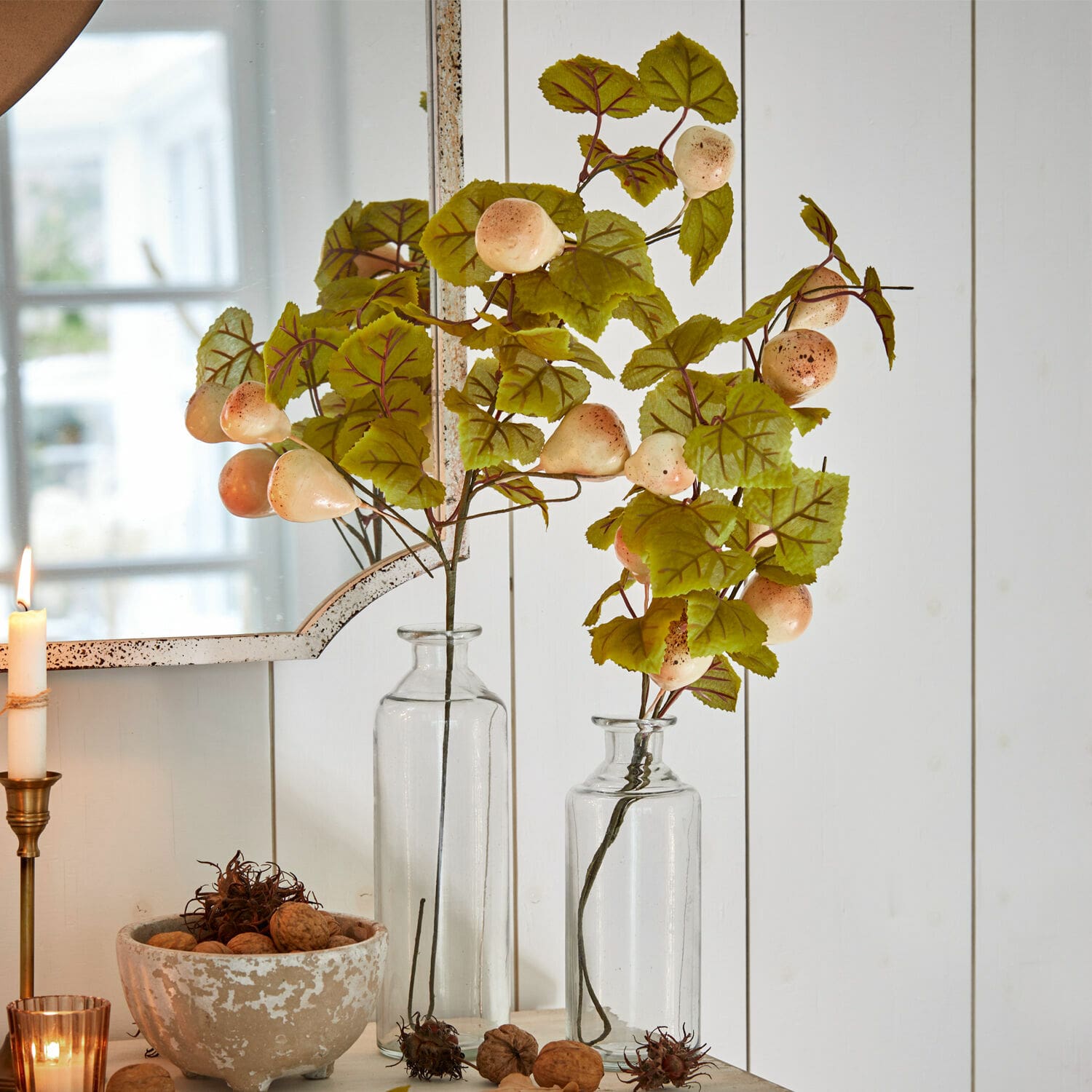 Decoratieve tak set van 2 Aidan Decoratieve takken met groene bladeren en crèmekleurige vruchten in doorzichtige glazen vazen tegen een witte achtergrond