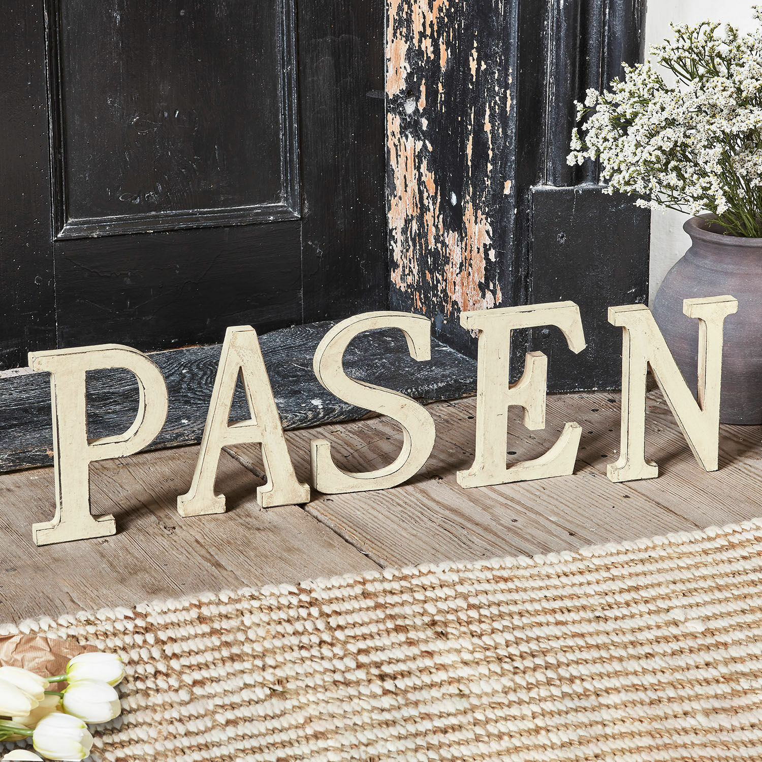 Sierletters PASEN Decoratieve crèmekleurige houten letters die het woord PASEN vormen op een rustieke houten vloer