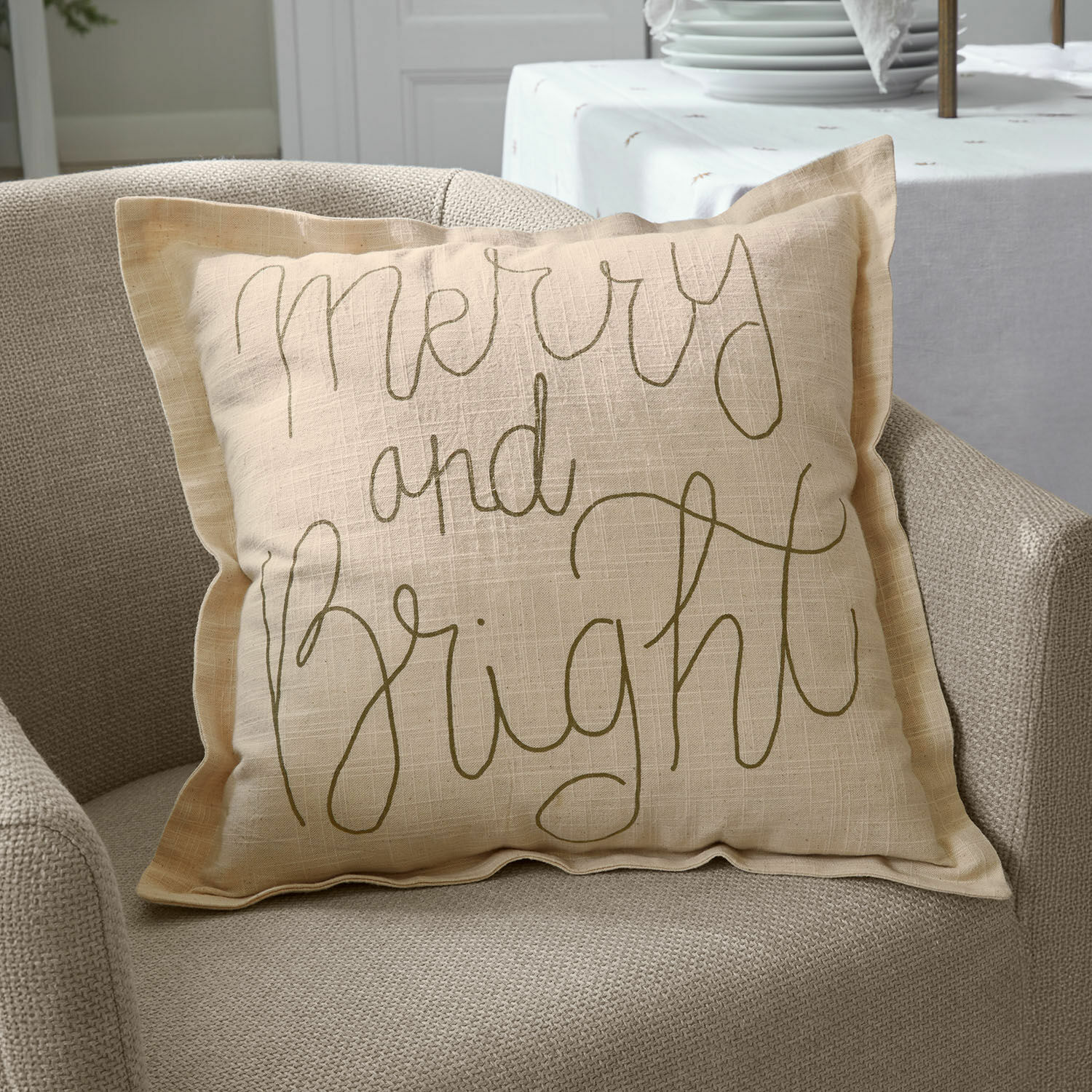 Kussenhoes Torvenna Beige linnen sierkussen met tekst Merry and Bright op beige fauteuil, woondecoratie