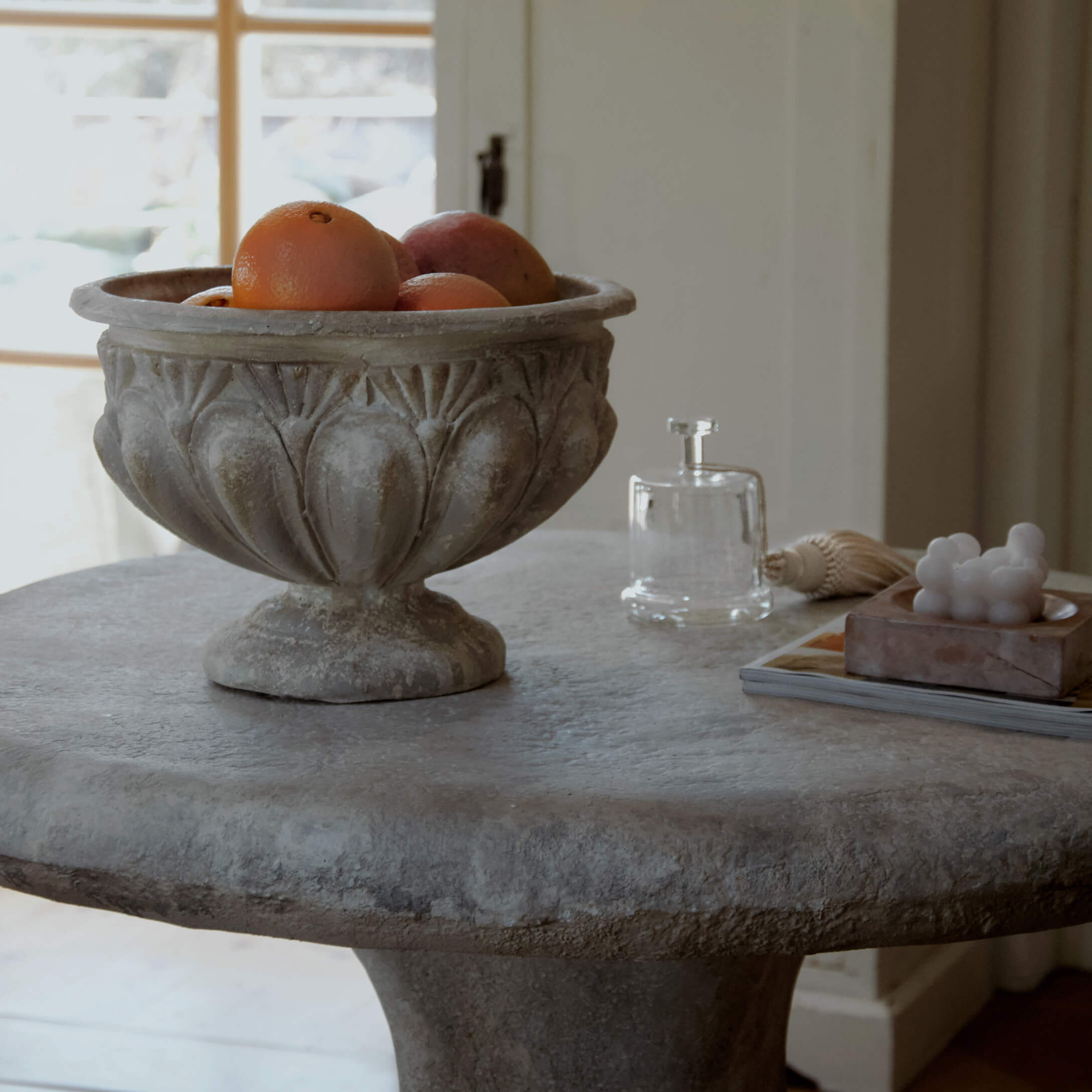 Decoratieve stenen schaal met sinaasappels op stenen tafel in lichte kamer