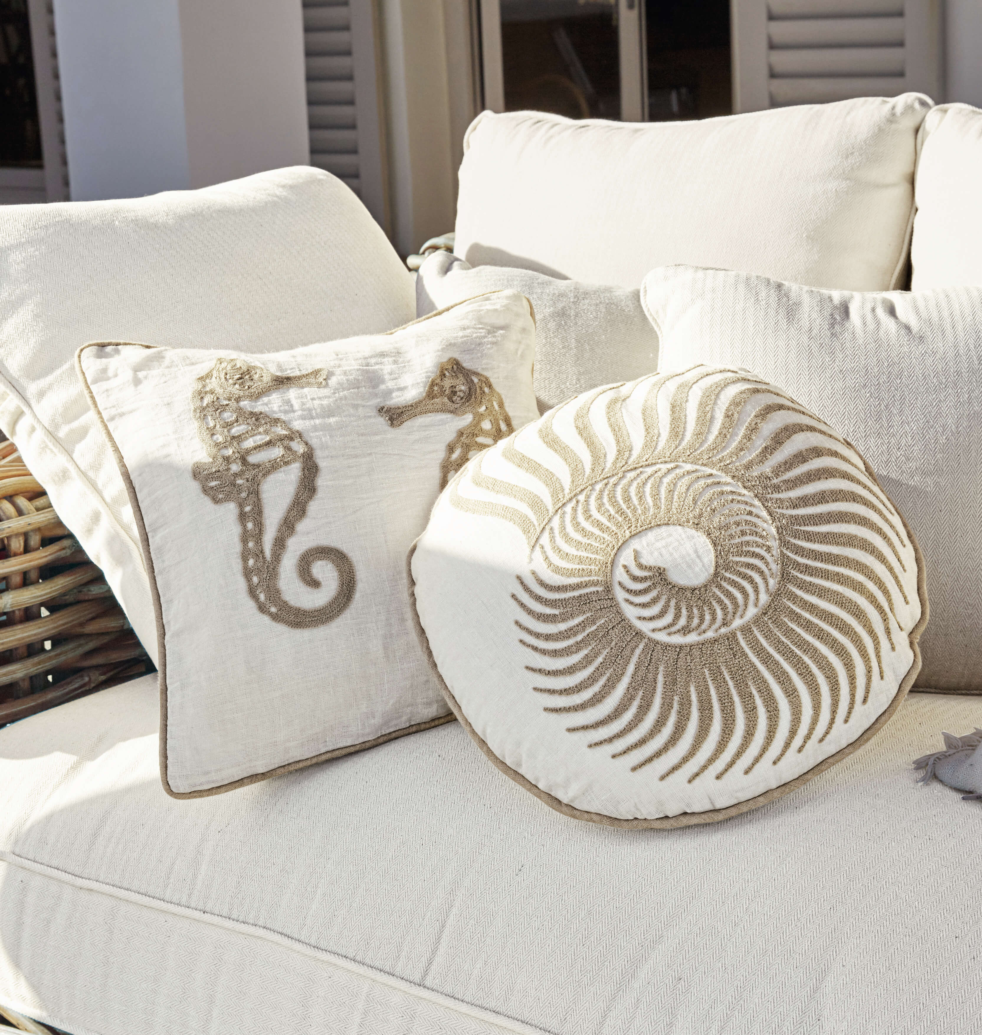 Beige sierkussens met zee-thema op lichte bank, woontextiel