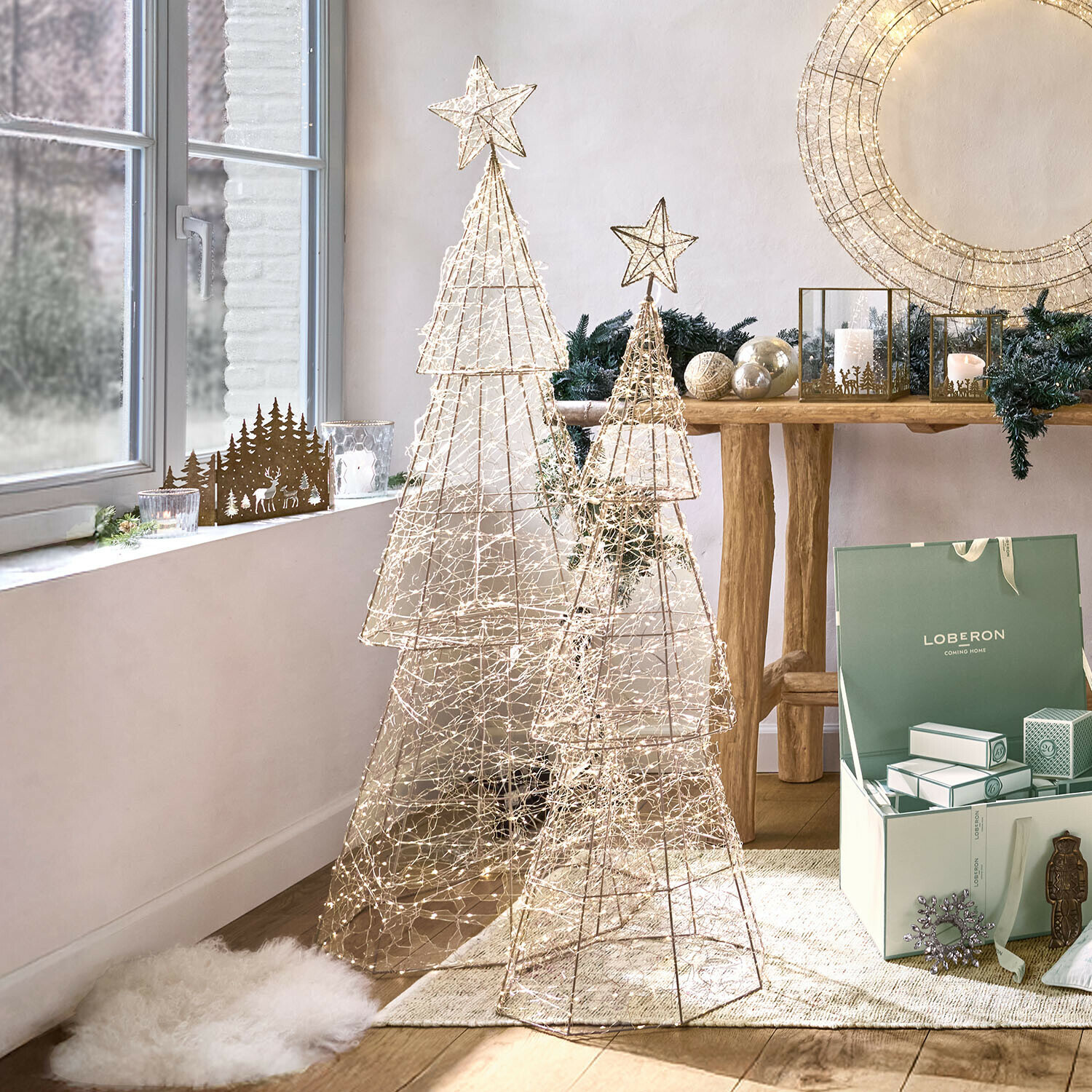 Twee decoratieve kerstbomen van metalen gaas met LED-lichtjes in lichte kamer met kerstdecoratie