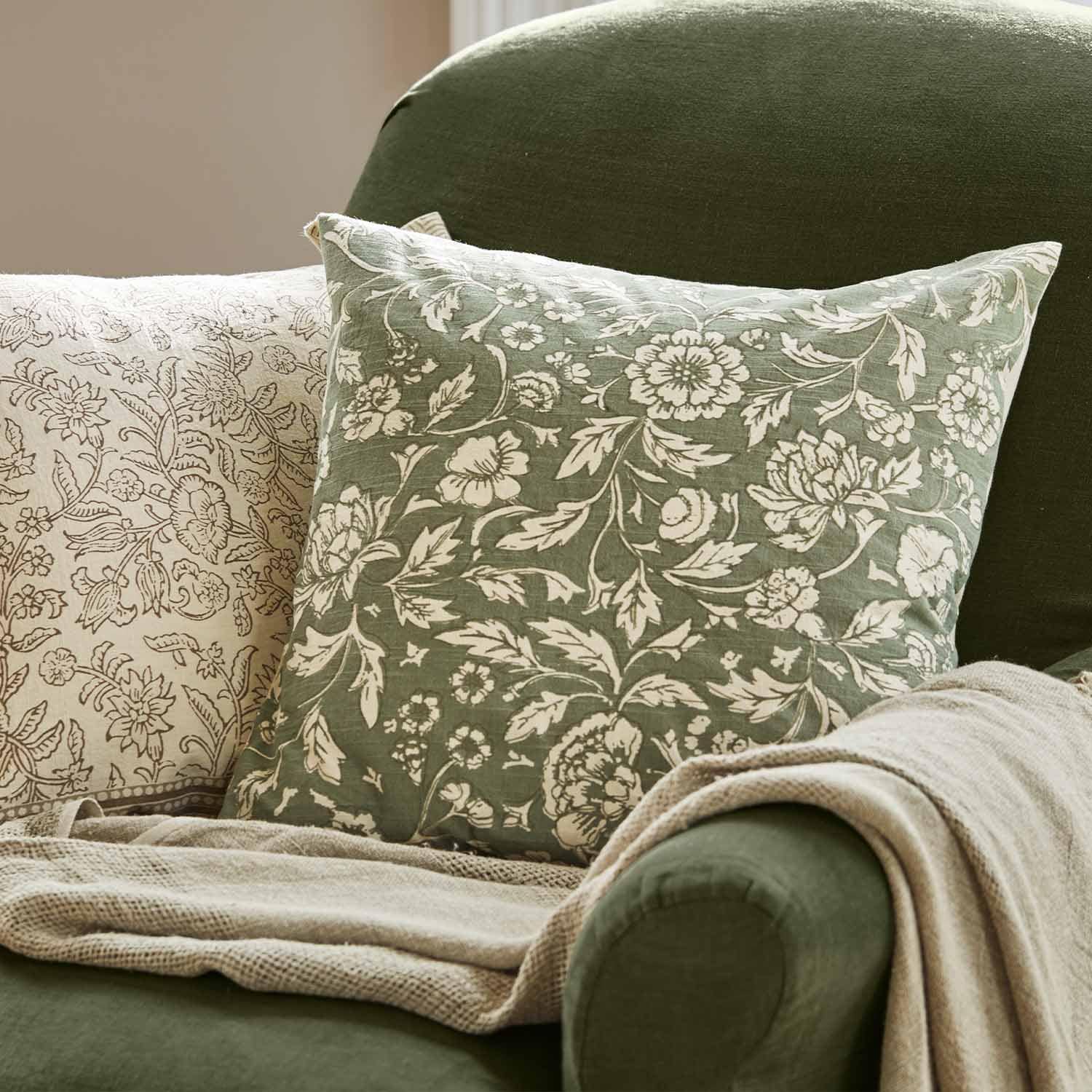 Groen sierkussen met wit bloemenpatroon op groene stoel met beige deken voor interieurdecoratie