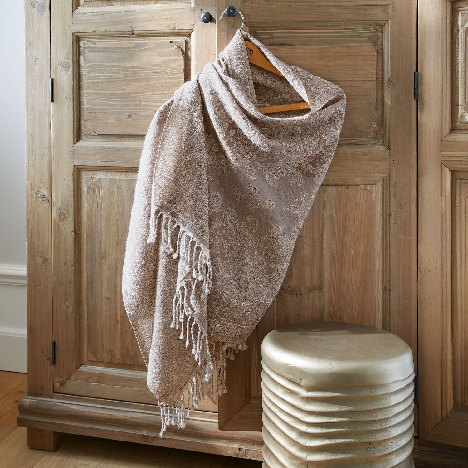Sjaal Rahmira Beige sjaal met paisley patroon en franjes aan houten kast, zacht materiaal, decoratief accessoire