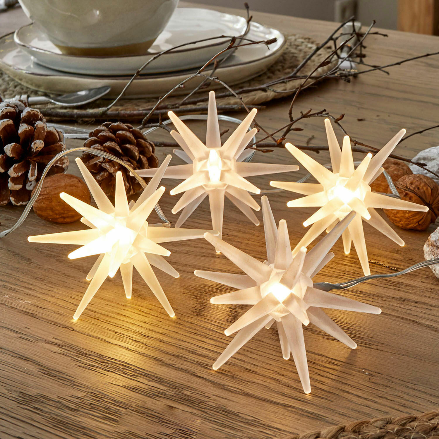 Decoratieve witte kunststof sterverlichting op houten tafel met natuurlijke decoraties