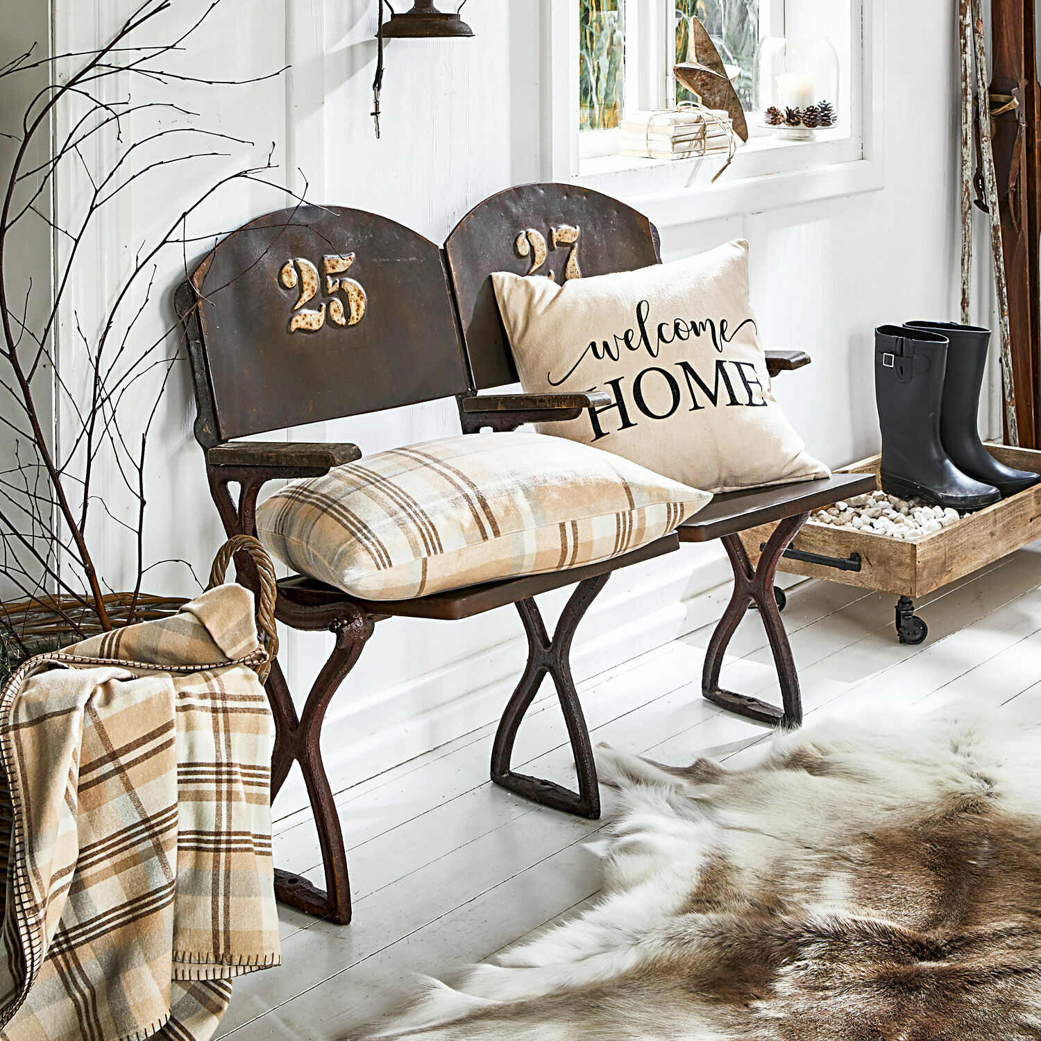 Metalen bank met nummers 25 en 27, beige kussen en geruit plaid in gezellige ruimte met bontkleed