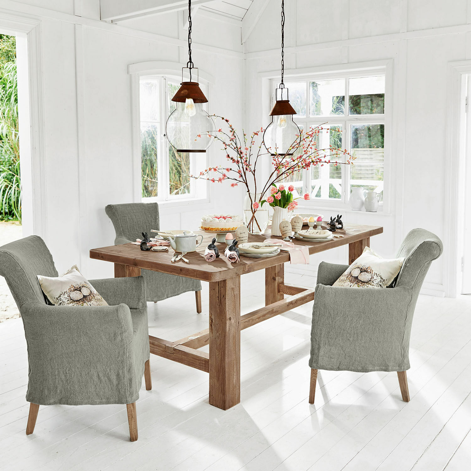Tafel Oteley Eetkamer met houten tafel en grijze gestoffeerde stoelen in een lichte, moderne ruimte