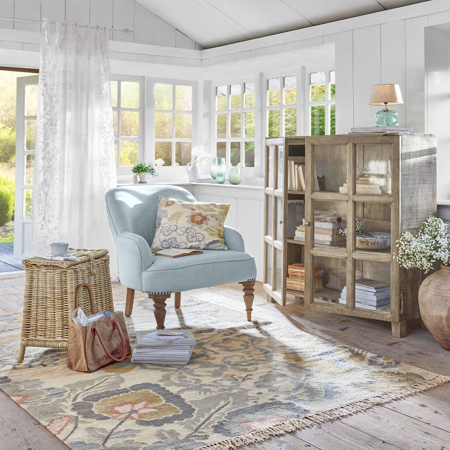 Gezellige kamer met lichtblauwe fauteuil, houten kast en decoratief bloemenkleed