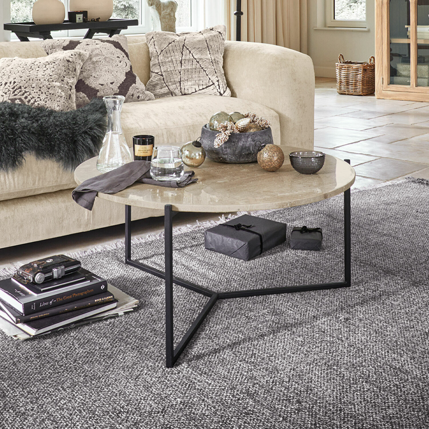 Salontafel Émorieux Ronde salontafel met beige marmeren blad en zwart metalen onderstel op grijs vloerkleed