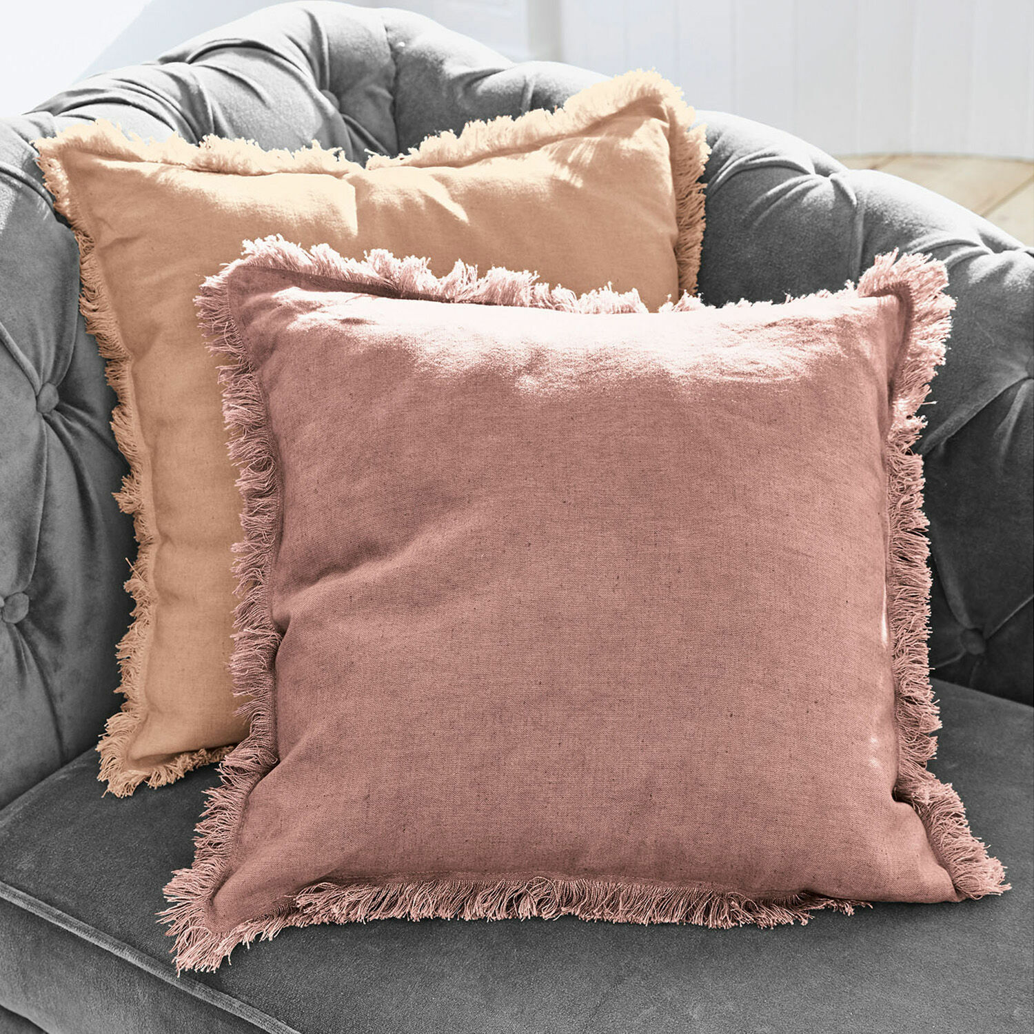 Kussenhoes set van 2 Quebo Set van twee linnen sierkussens met franjes in roze en beige op een grijze bank