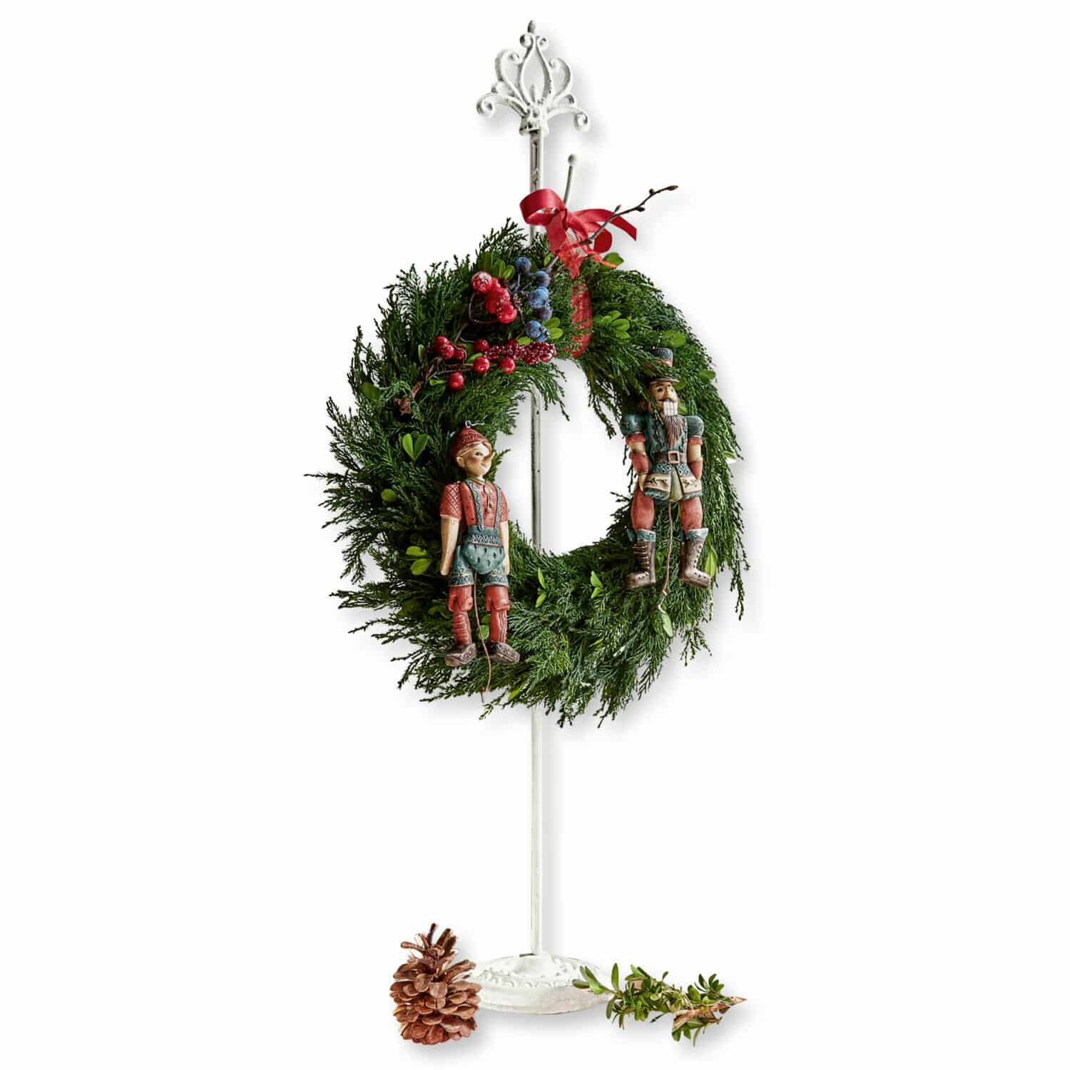 Kransenstandaard Irulan Kerstkrans van groene takken met rode en blauwe bessen, houten figuren, op witte standaard