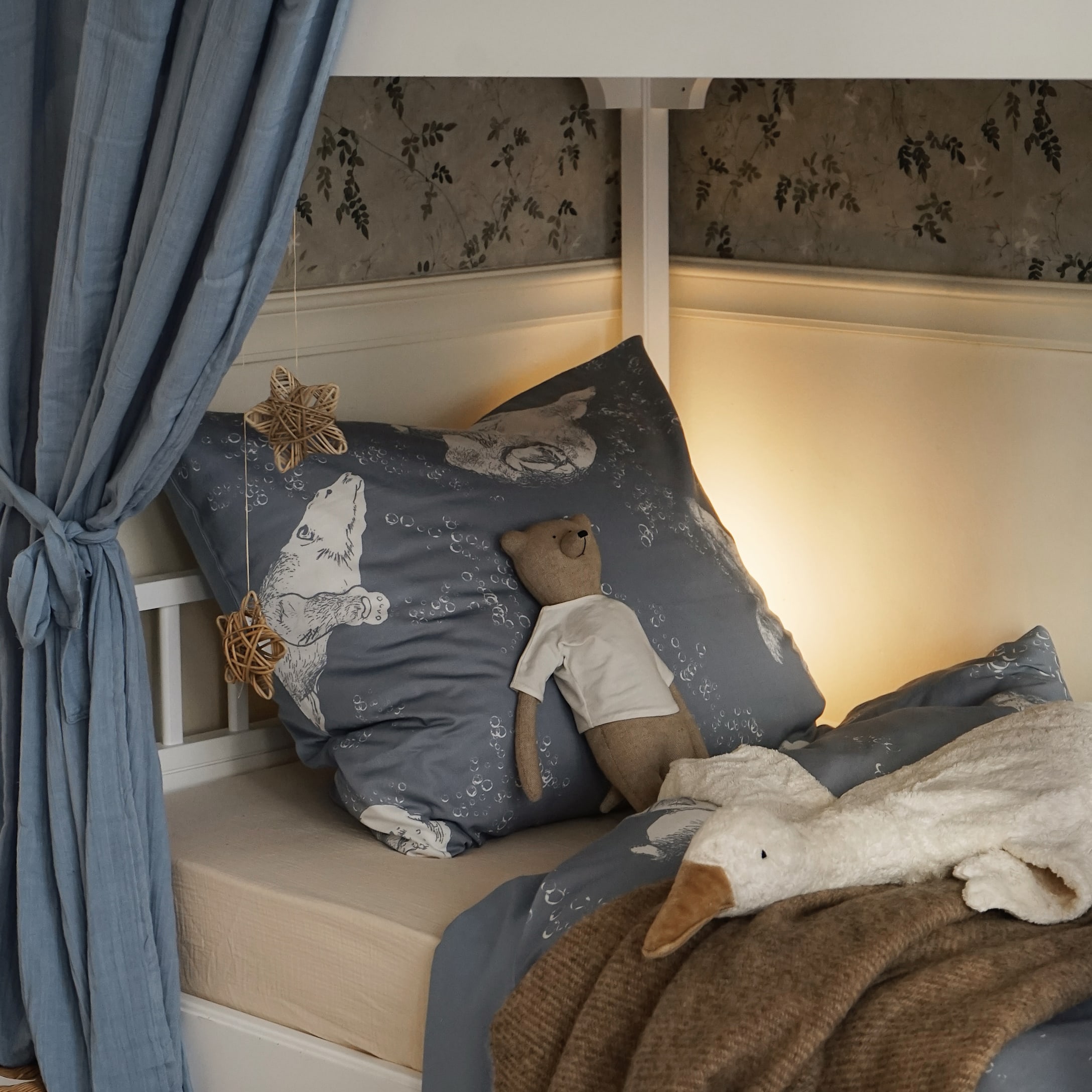 Blauw beddengoed met berenmotief en knuffels op een bed in een gezellige kinderkamer