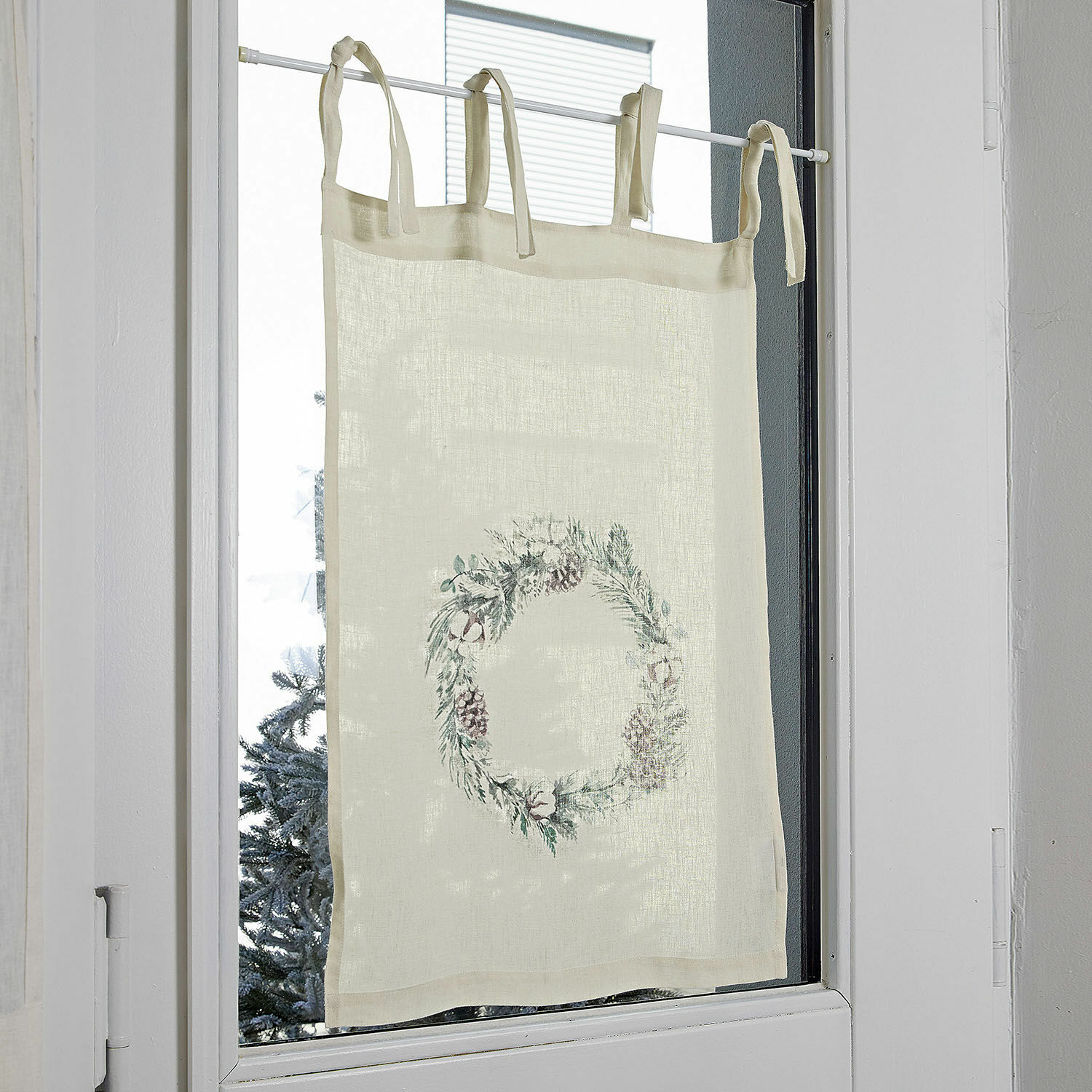 Beige linnen gordijn met decoratieve krans van dennenappels en takken voor raam