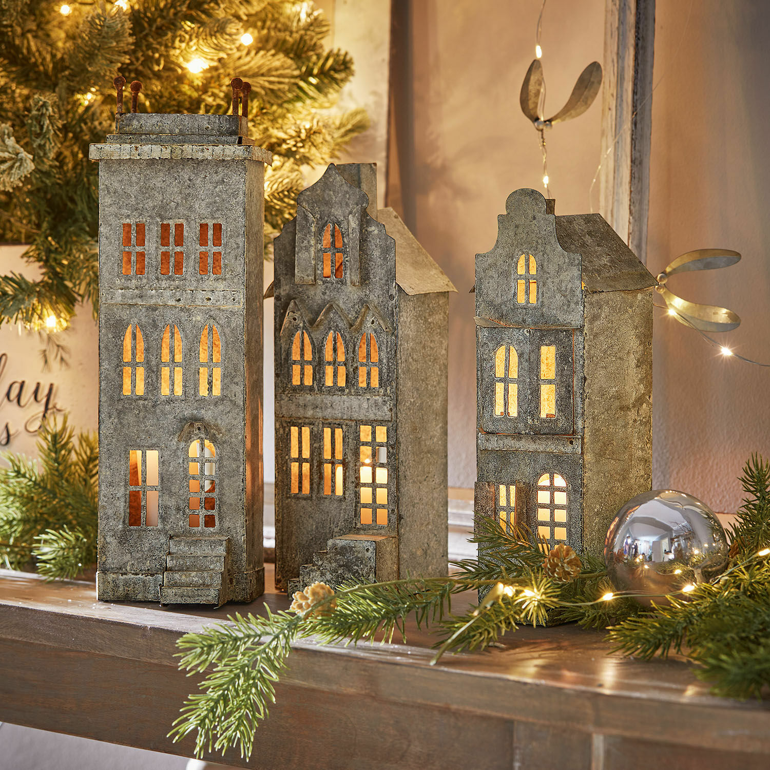 Decoratieve metalen lantaarns in de vorm van grijze huisjes met warm licht, feestelijke kerstdecoratie