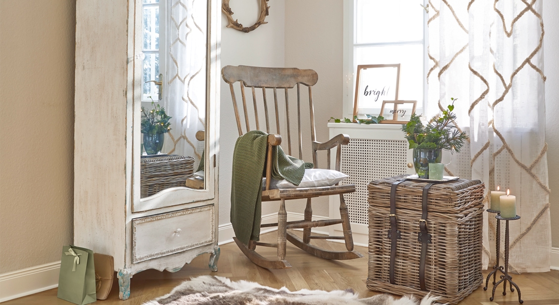 Gezellige hoek met houten schommelstoel en rieten tafel in zachte natuurlijke kleuren