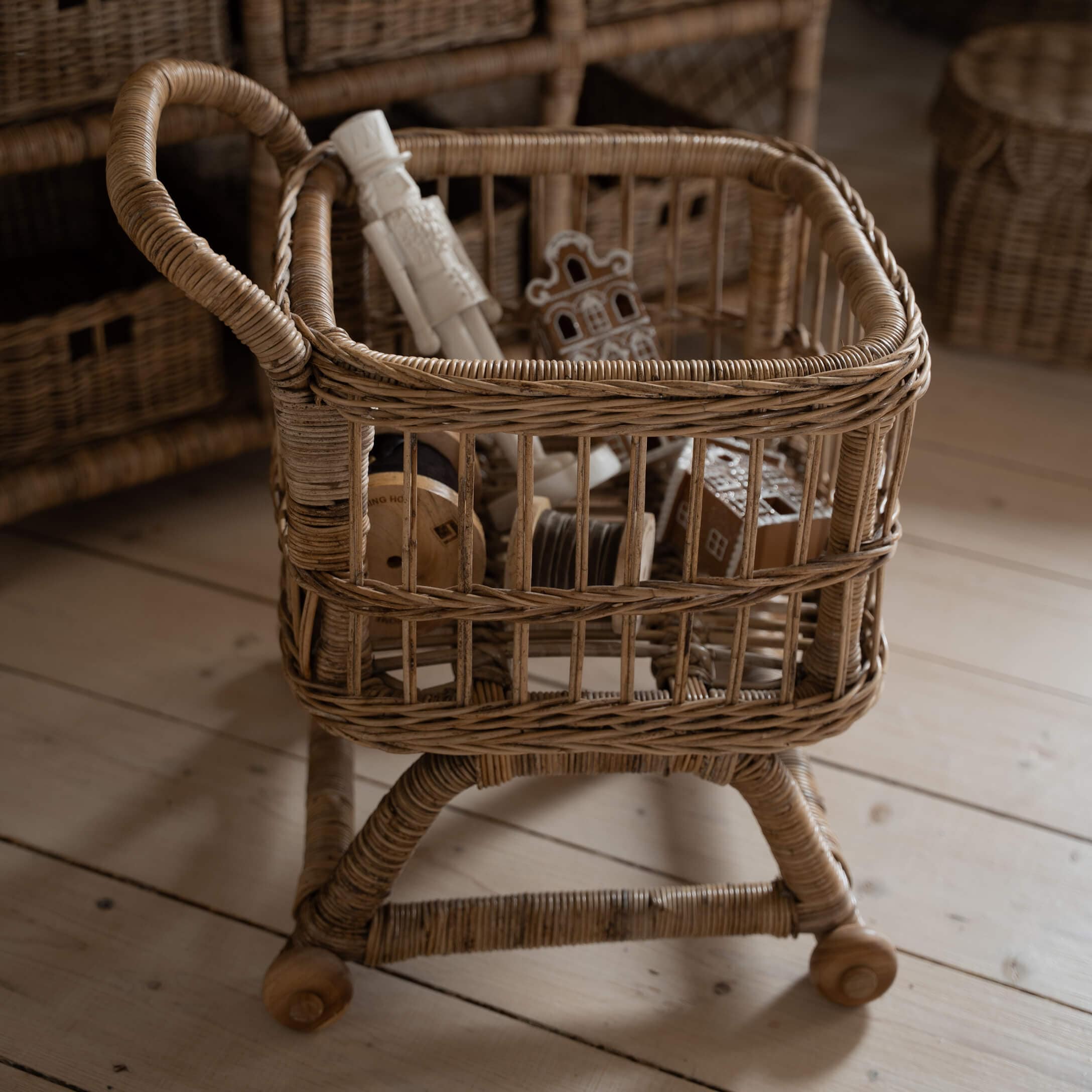 Rieten mand op wieltjes met houten handvat in natuurlijke kleur, voor het opbergen van decoratie en accessoires