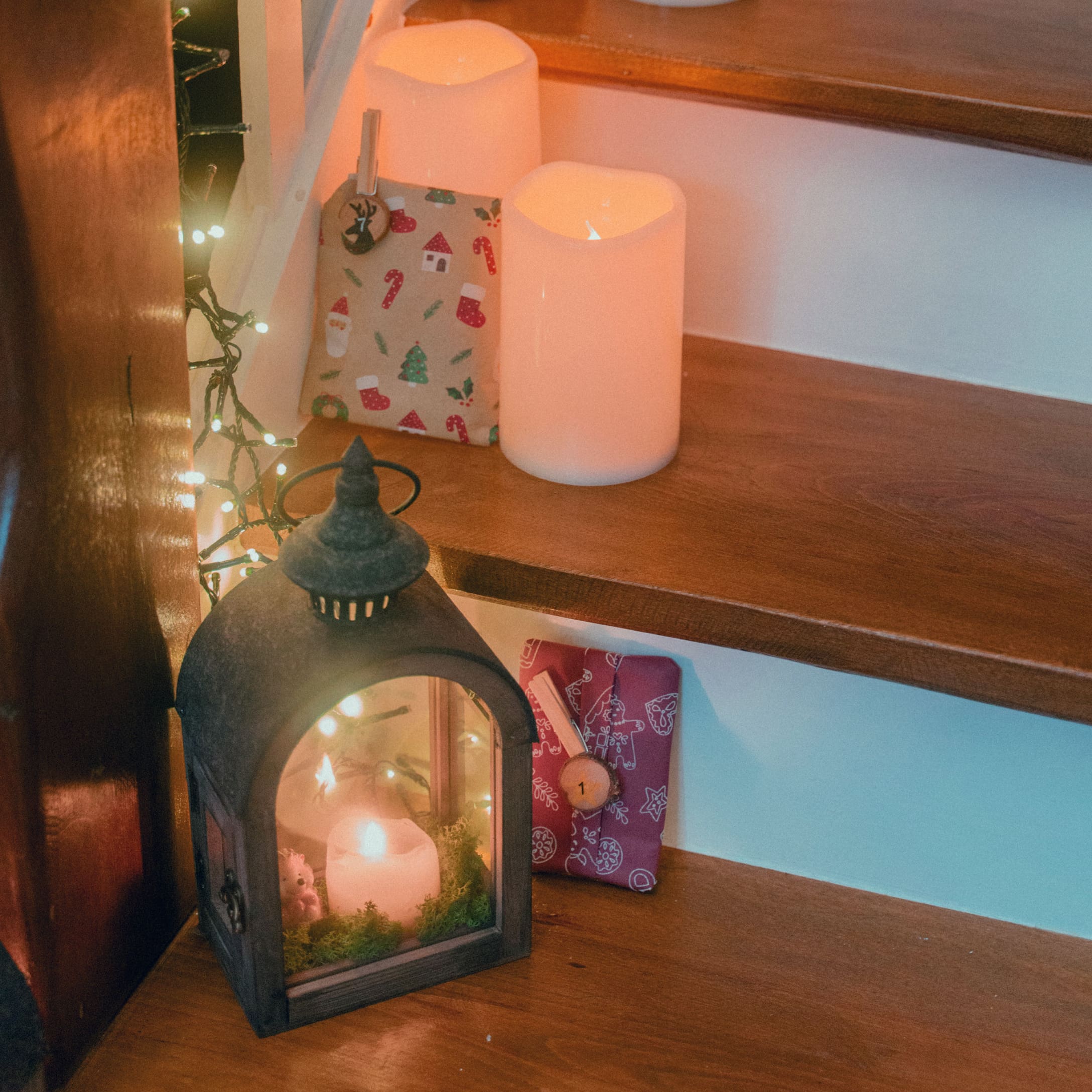 Metalen lantaarn met kaars en kerstcadeaus op verlichte houten treden