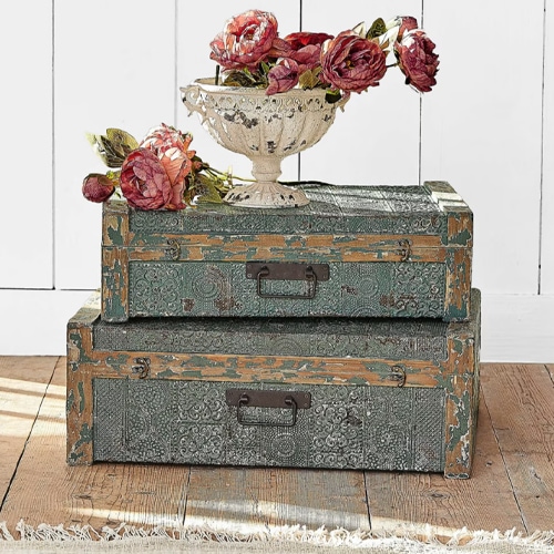 Set van twee decoratieve groene metalen kisten met een bloemenvaas erop