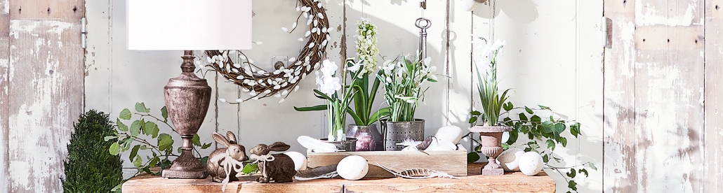 Rustieke paasdecoratie met houten tafel, witte bloemen en natuurlijke versieringen