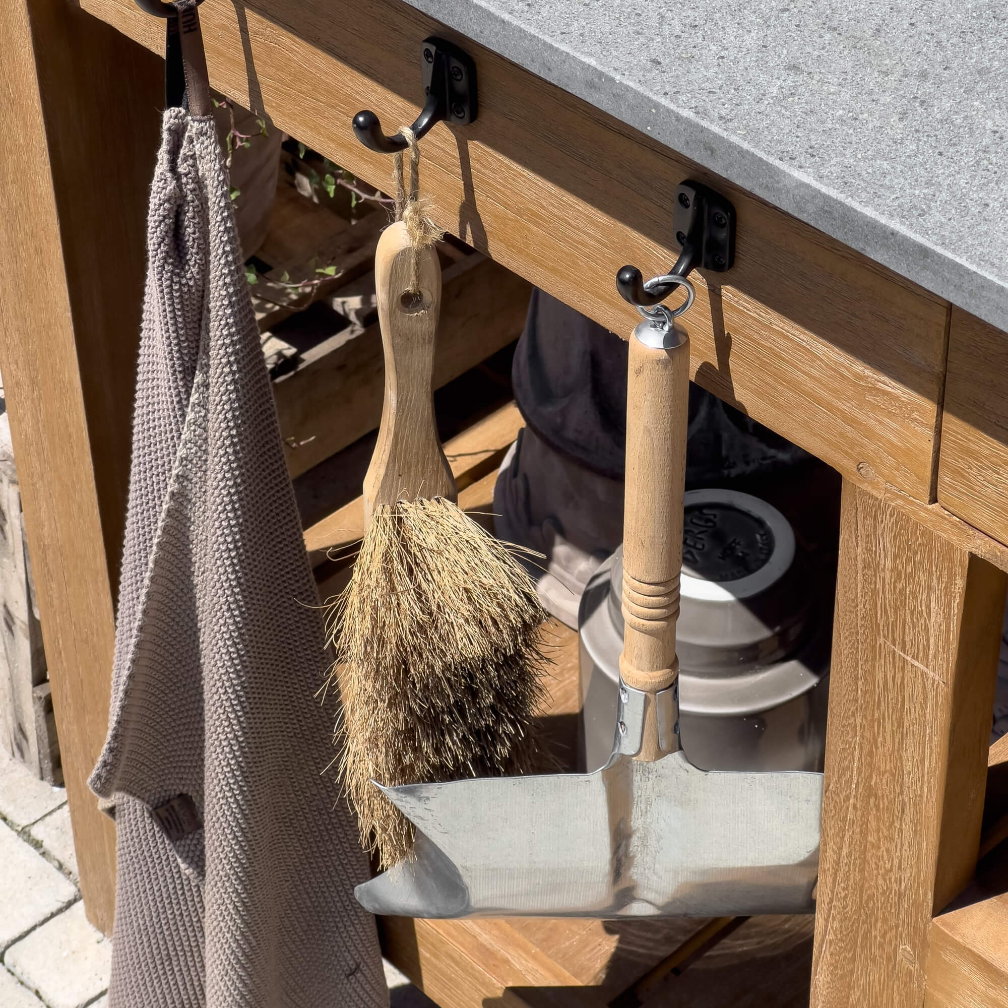 Borstel met natuurlijke haren en metalen schep met houten handvat hangend onder houten werkblad