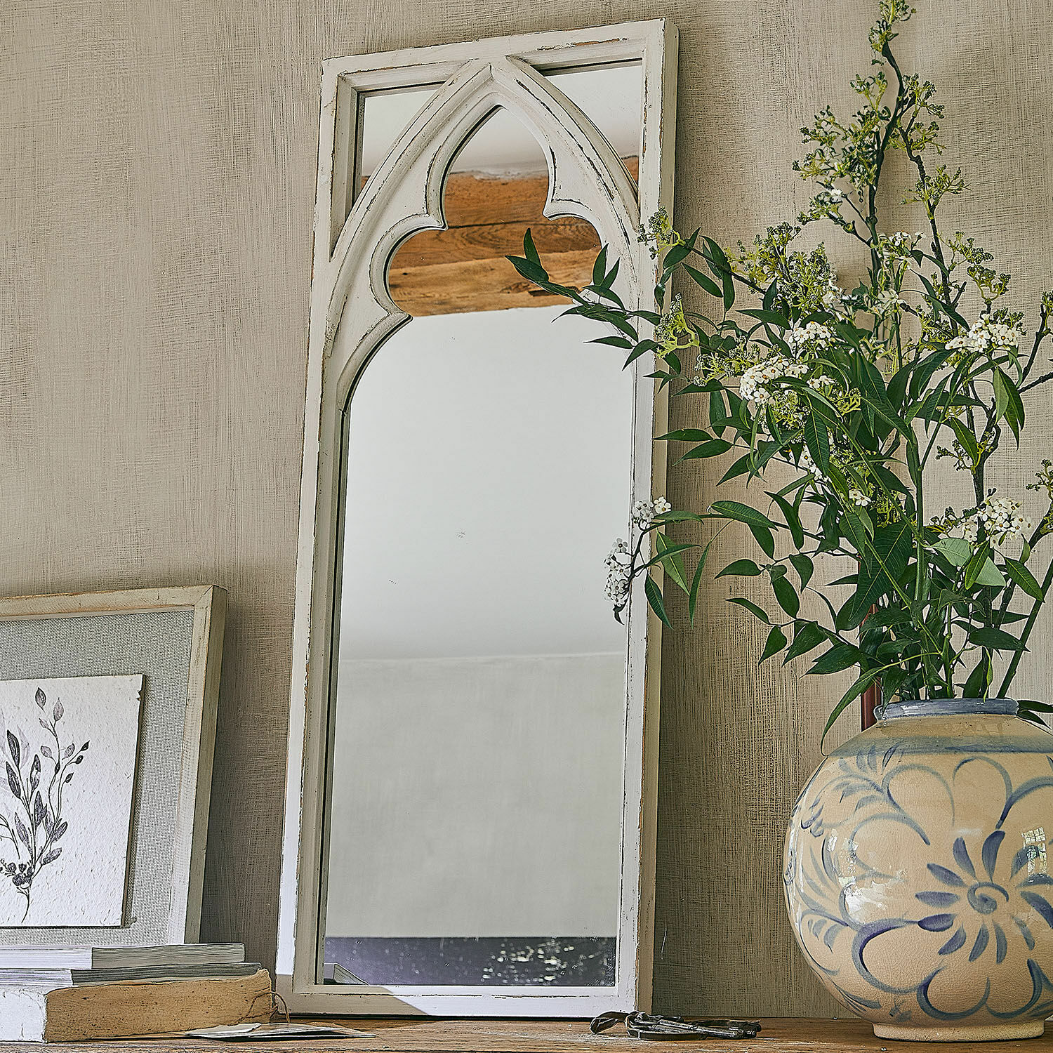 Spiegel Golvine Witte houten spiegel met gotisch boogpatroon op houten tafel naast decoratieve vaas met bloemen