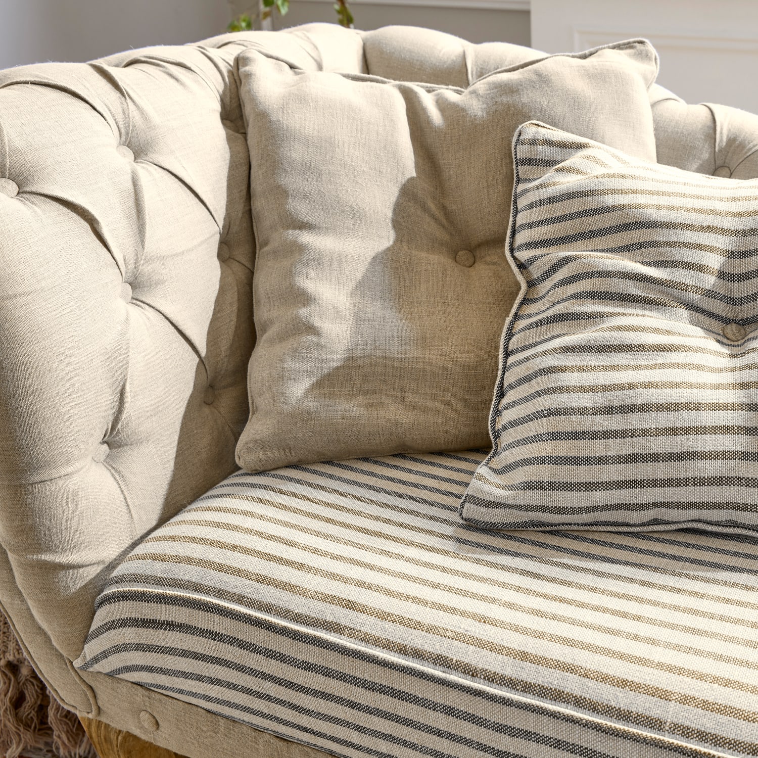 Beige gestoffeerde bank met gestreepte en effen kussens, zachte stof, comfortabele meubel
