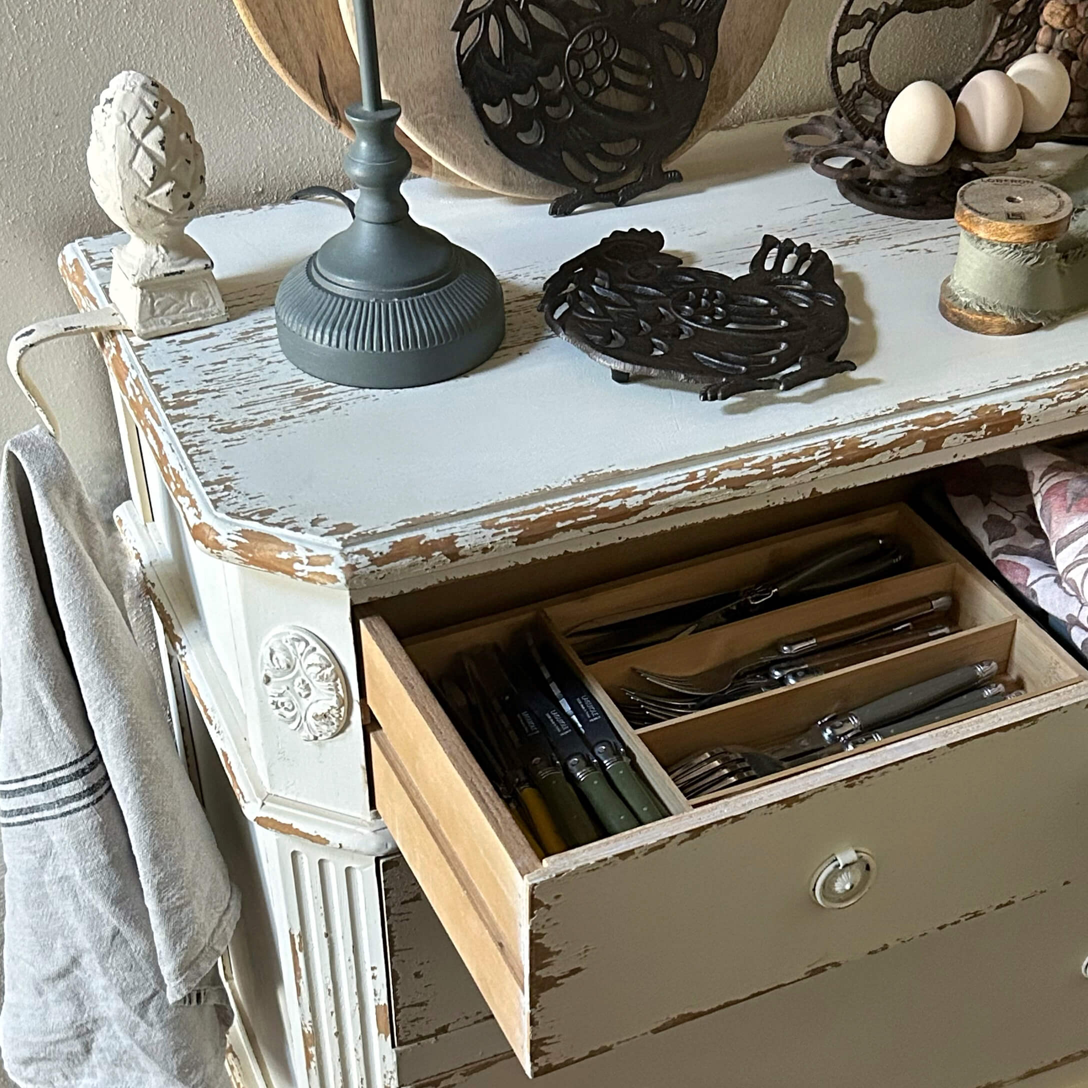 Witte verweerde houten ladekast met open lade en bestekorganizer, rustieke keukenstijl