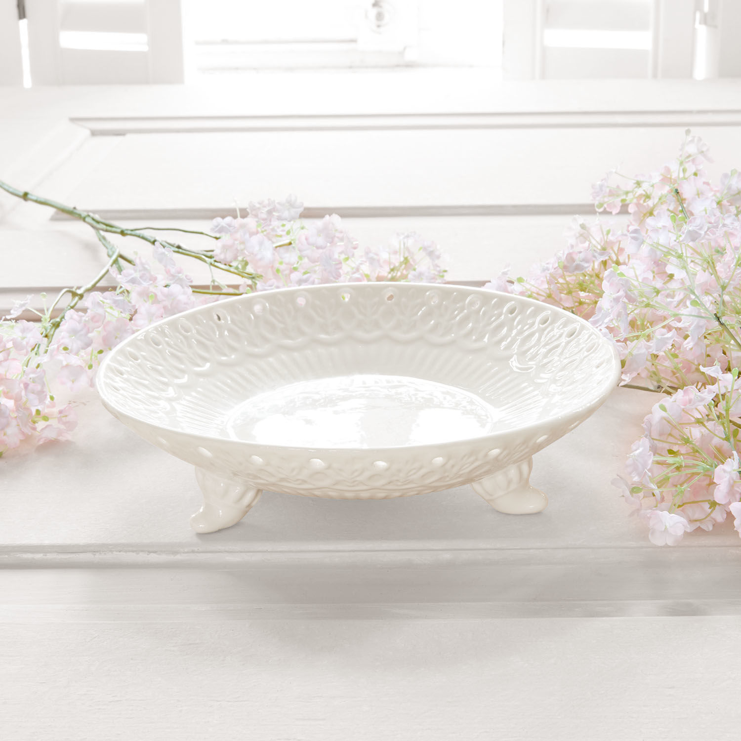 Witte keramische schaal op pootjes met decoratief patroon, stijlvolle woondecoratie