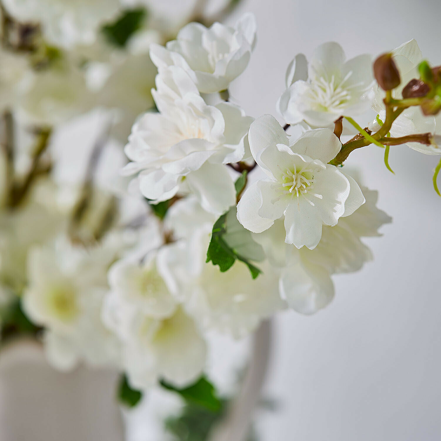 Witte kunstbloemen met groene bladeren aan tak voor interieurdecoratie
