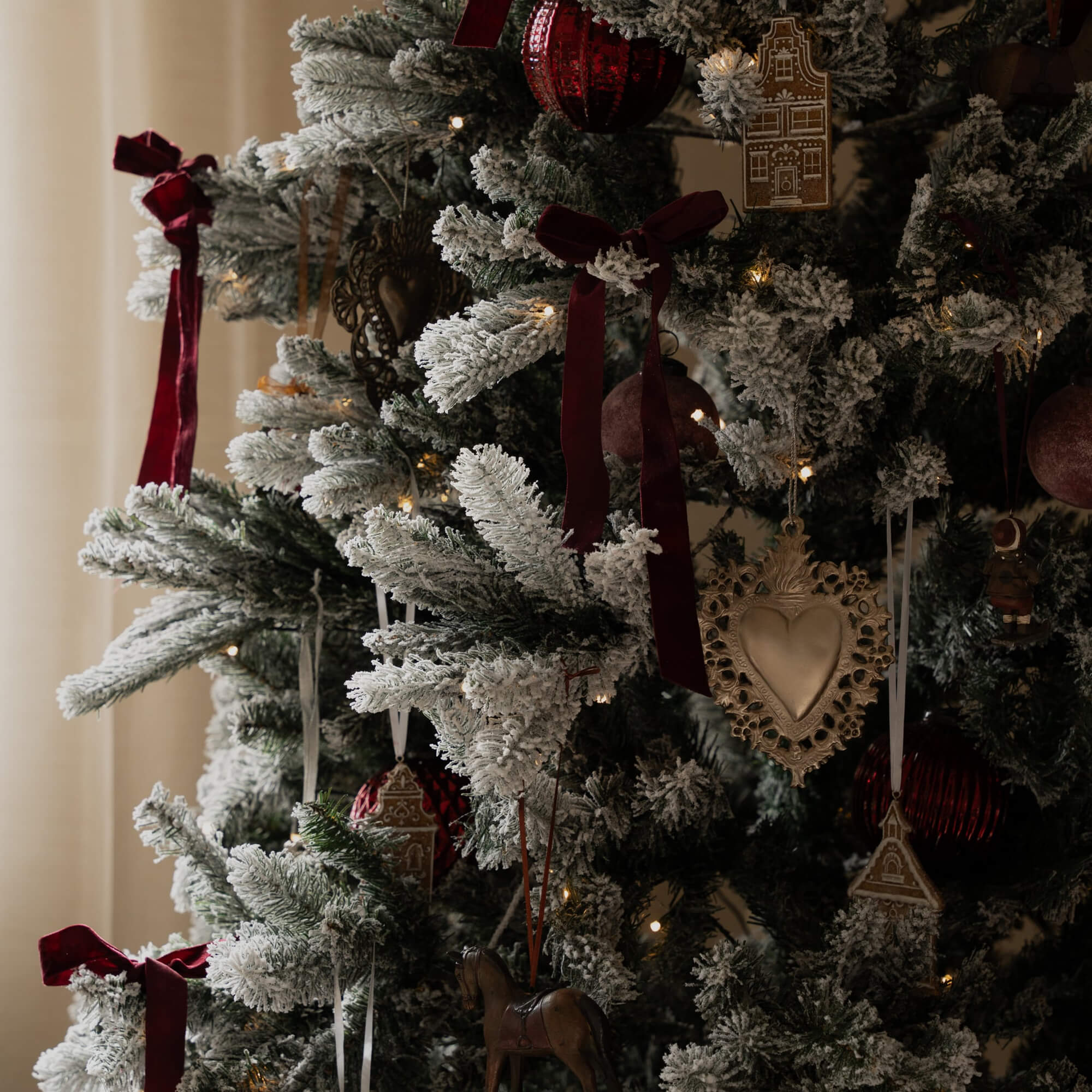 Kunstkerstboom met wit sneeuw effect, rode linten en traditionele kerstversieringen