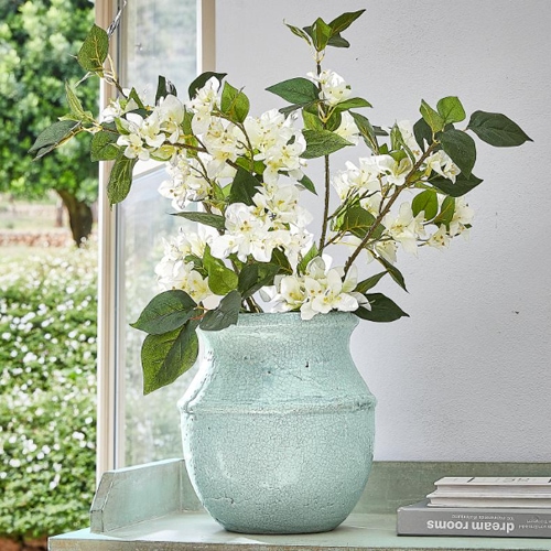 Mintgroene keramische vaas met witte bloemen op tafel, natuurlijke interieurdecoratie