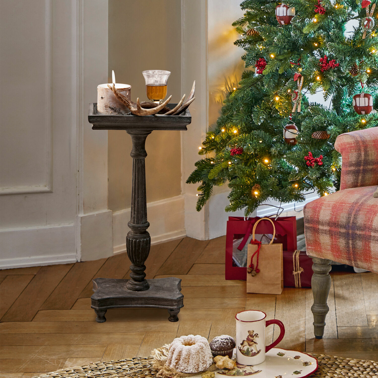 Donkere houten standaard met kaars en gewei decoratie bij versierde kerstboom en cadeaus