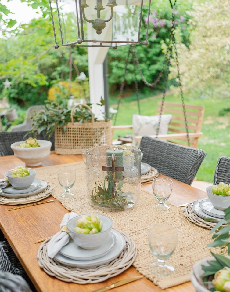 Tuin tafel van natuurlijk hout met gevlochten placemats en kaarsdecoratie in glazen vaas