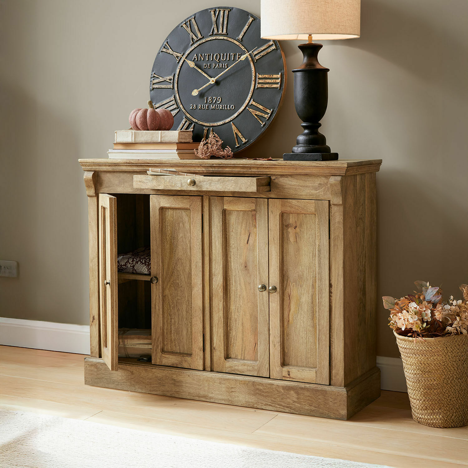 Houten dressoir in natuurlijke kleur met lade en deuren, decoratieve klok en lamp erop