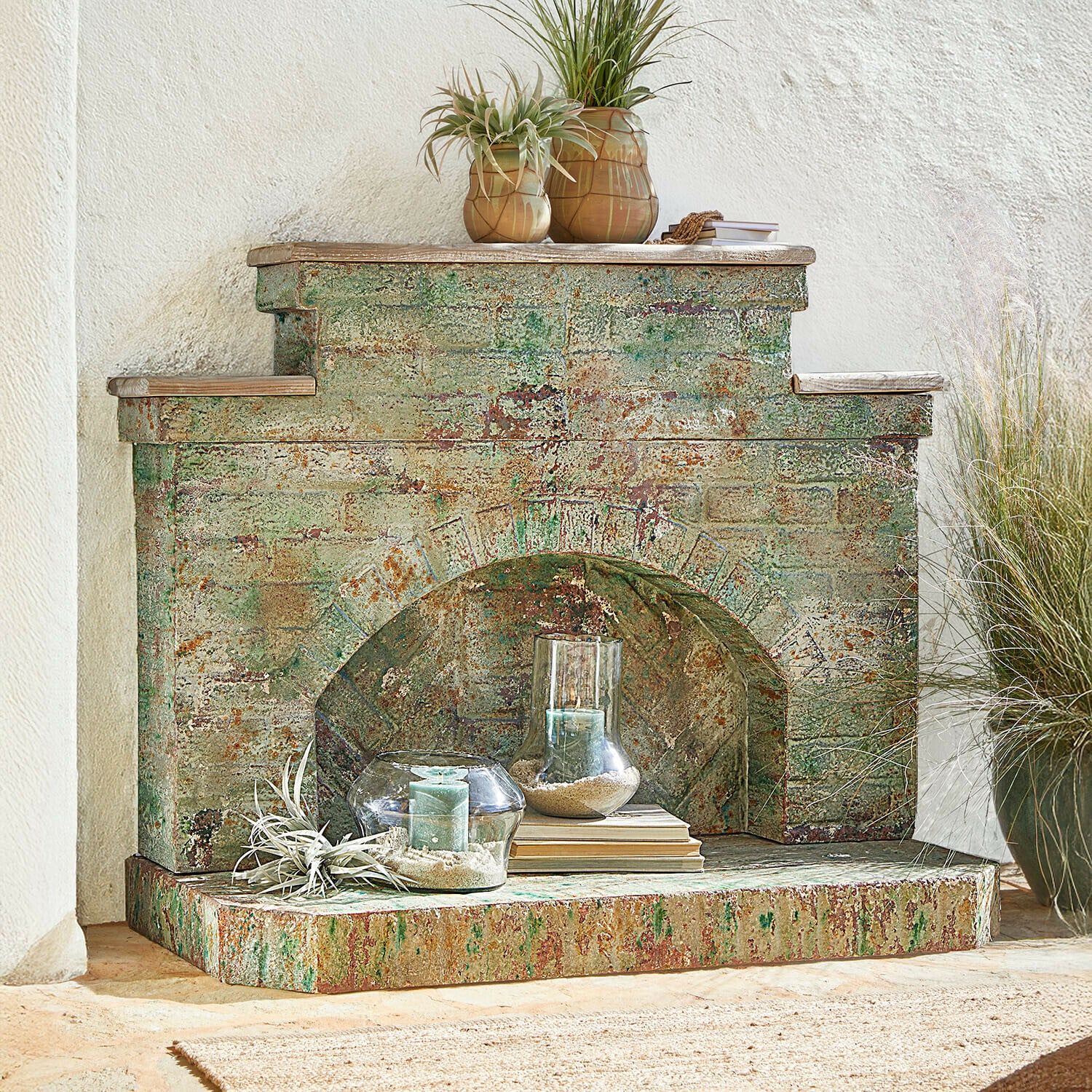 Haardschouw Kestonbury Decoratieve open haard van verouderd metaal in groen-roesttinten met kaarsen en planten