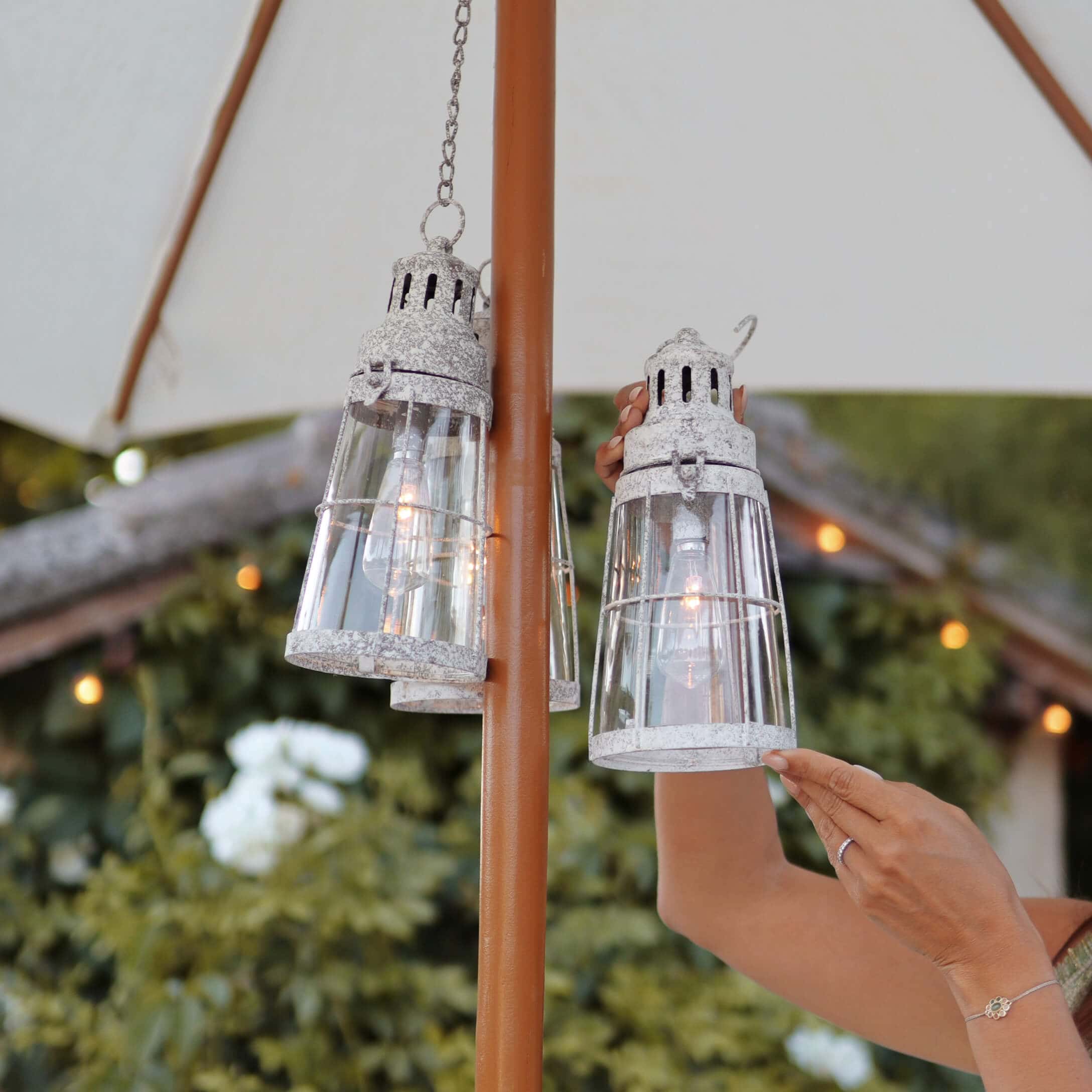 Glazen lantaarn met wit verweerd metaal, hangend aan parasol, sfeervolle buitenverlichting