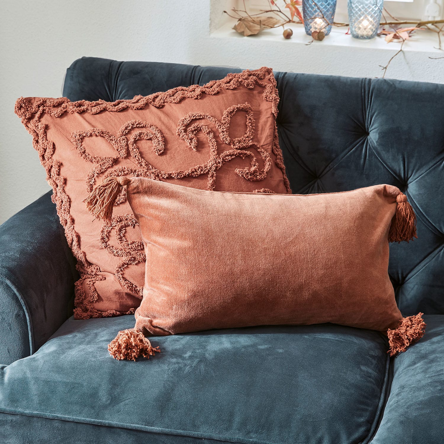 Twee decoratieve kussens van oranje fluweel op een donkerblauwe bank, zachte en stijlvolle woonaccessoires