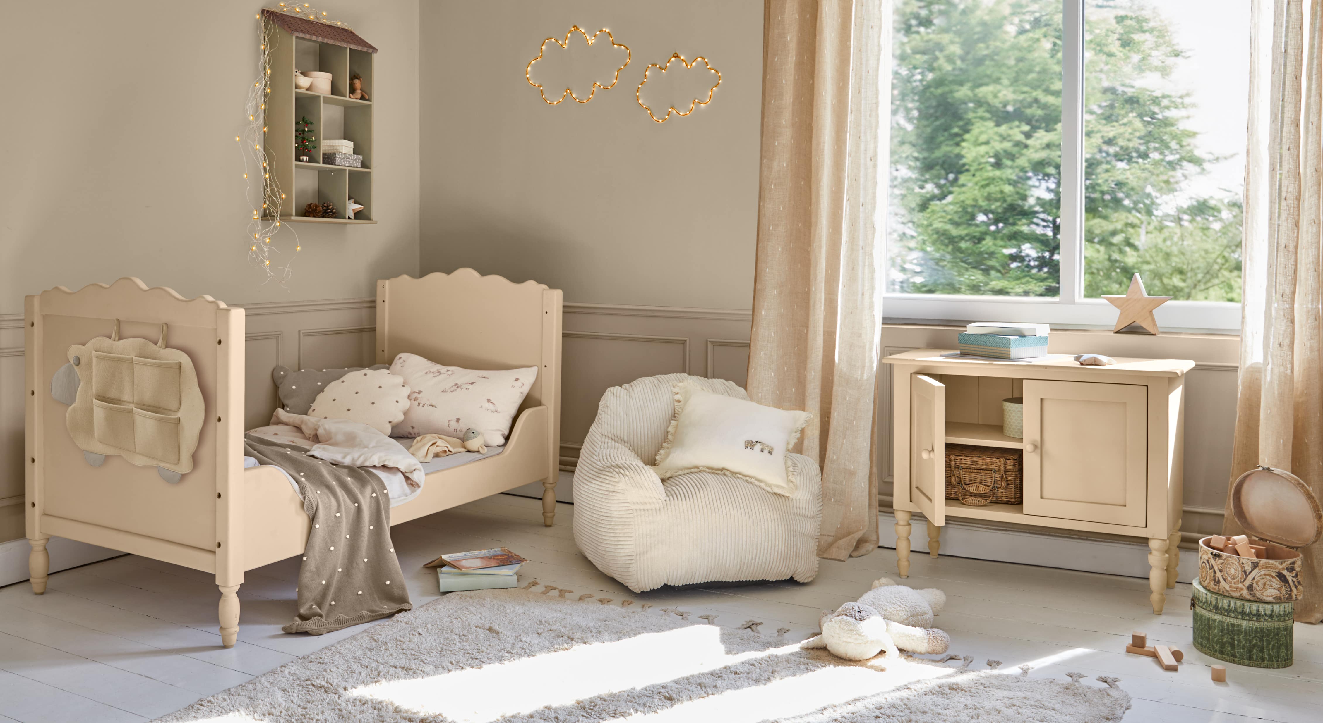Beige houten kinderbed met zachte kussens en bijpassende kast in lichte kinderkamer