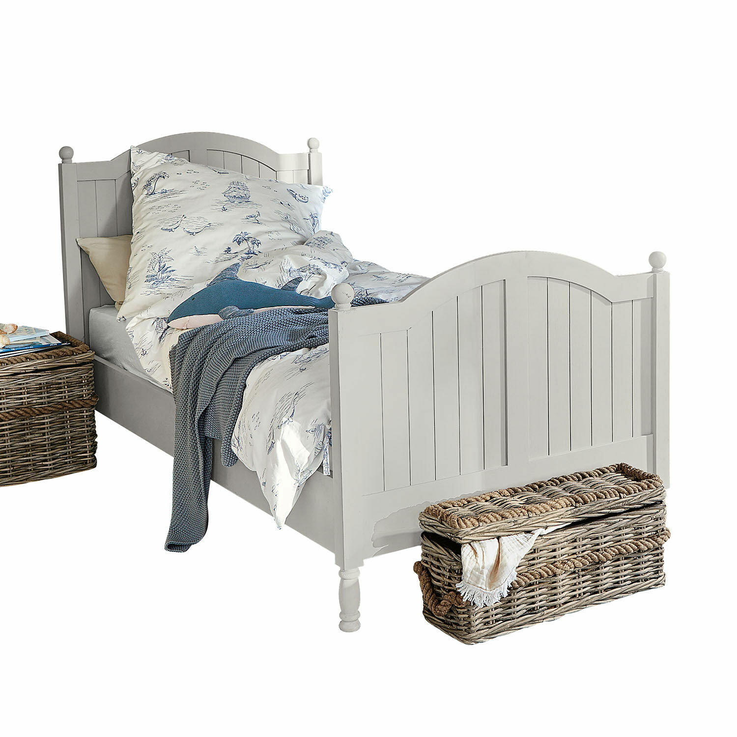 Bed Alarion Wit houten bed met decoratief hoofdeinde, blauw beddengoed met patroon en rieten mand ernaast