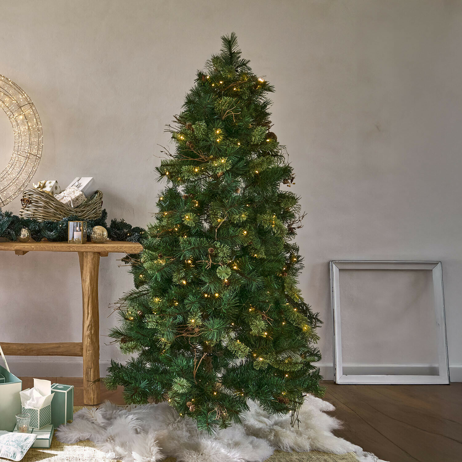 Ledkerstboom Yundra Kunstkerstboom met groene naalden en warme LED-verlichting op een wit bontkleed