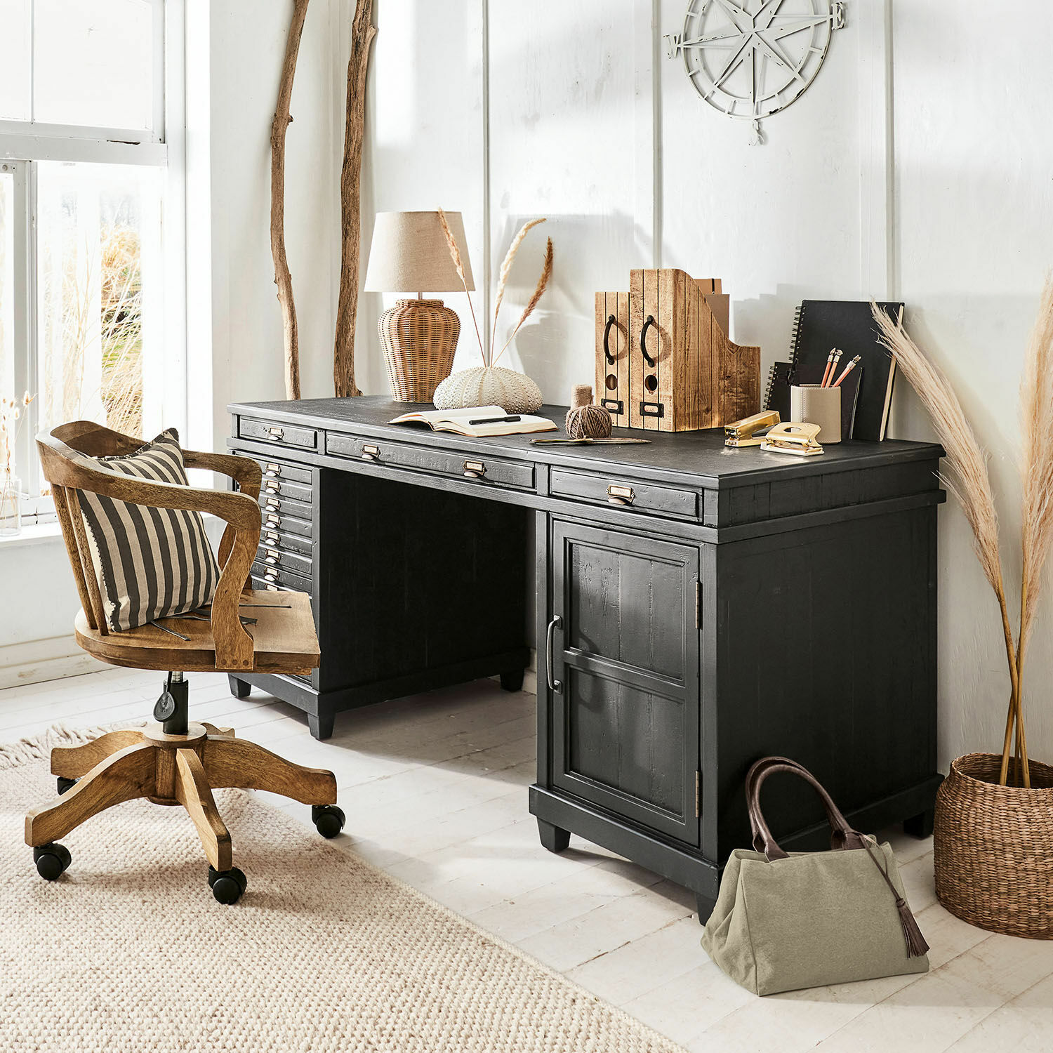 Bureau Brevilliers Zwart houten bureau met laden en decoratie in lichte, natuurlijke ruimte met bureaustoel op wieltjes
